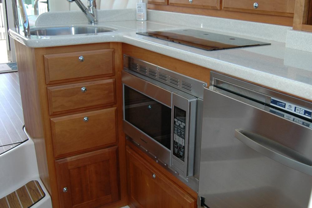2014 Back Cove 37 yacht kitchen with wooden cabinets, microwave, and stainless steel appliances.