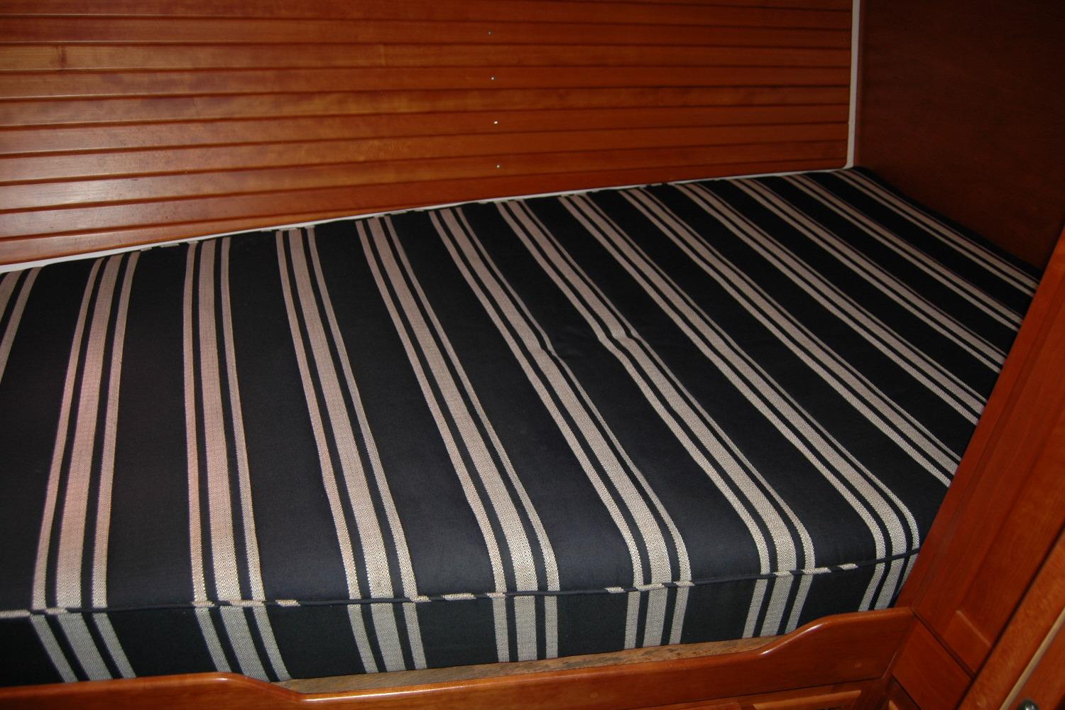 Striped mattress in 2014 Back Cove 37 boat cabin with wooden paneling.