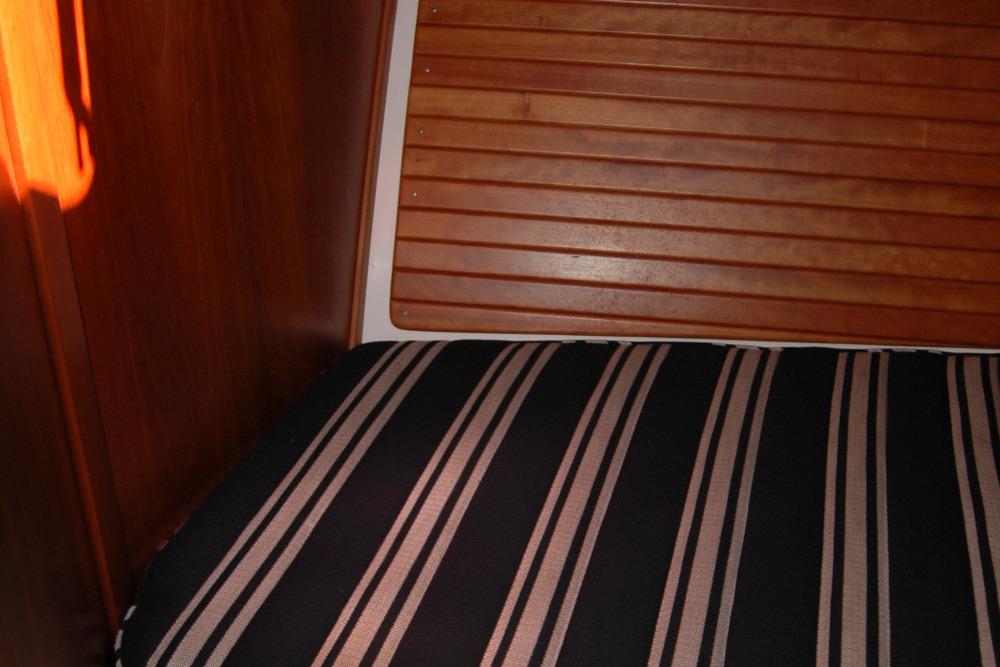 Interior of 2014 Back Cove 37 boat with striped cushion and wooden paneling.