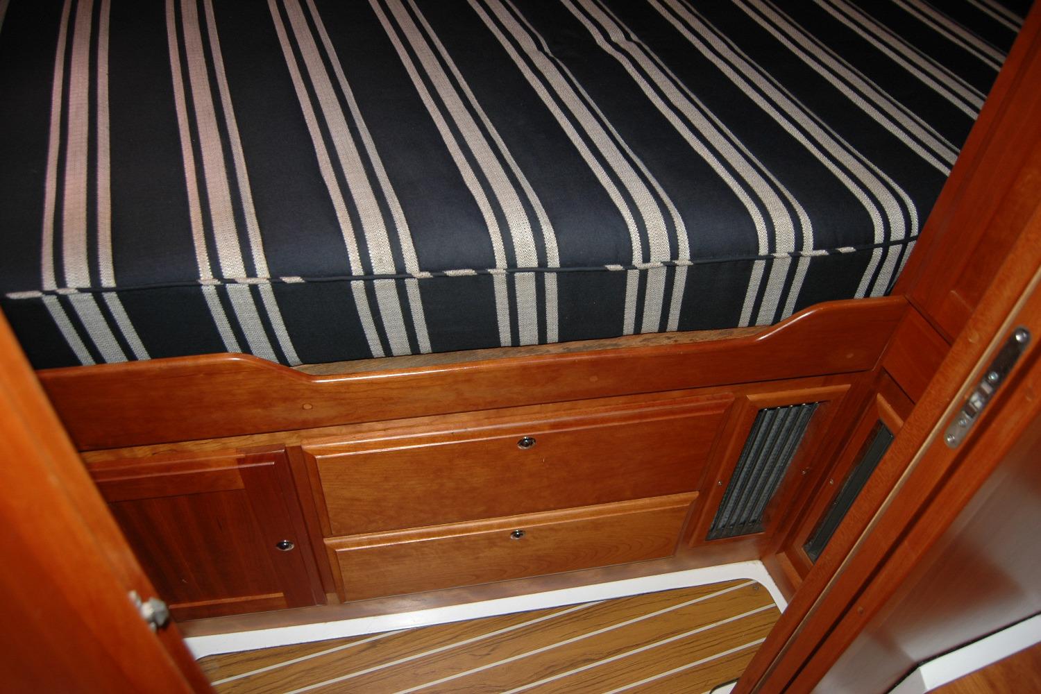 2014 Back Cove 37 interior with striped bedding and wooden cabinetry.