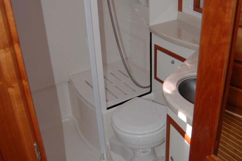 2014 Back Cove 37 yacht bathroom with shower, sink, and wooden cabinetry.
