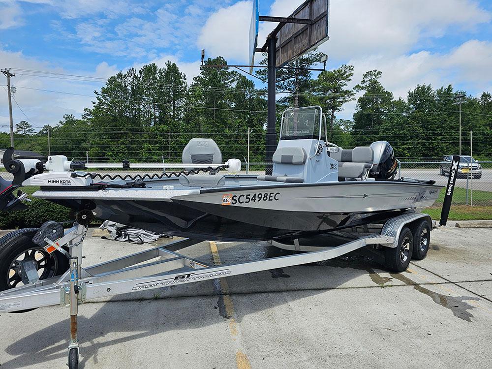 2023 Xpress H20B boat on trailer, parked outdoors, with trees in background.