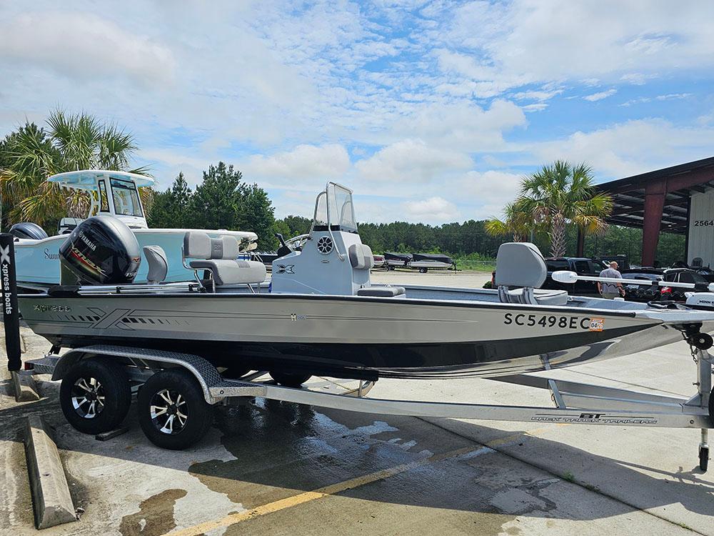 2023 Xpress H20B boat on trailer, parked outdoors under a partly cloudy sky.