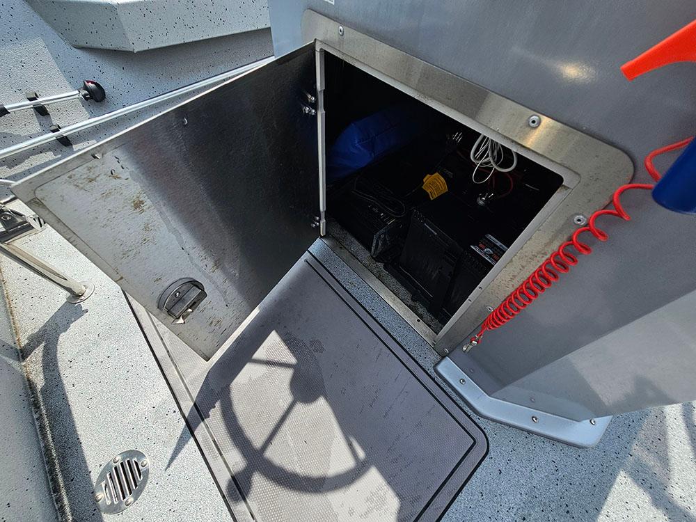Open storage compartment on 2023 Xpress H20B boat, showing interior equipment and wiring.