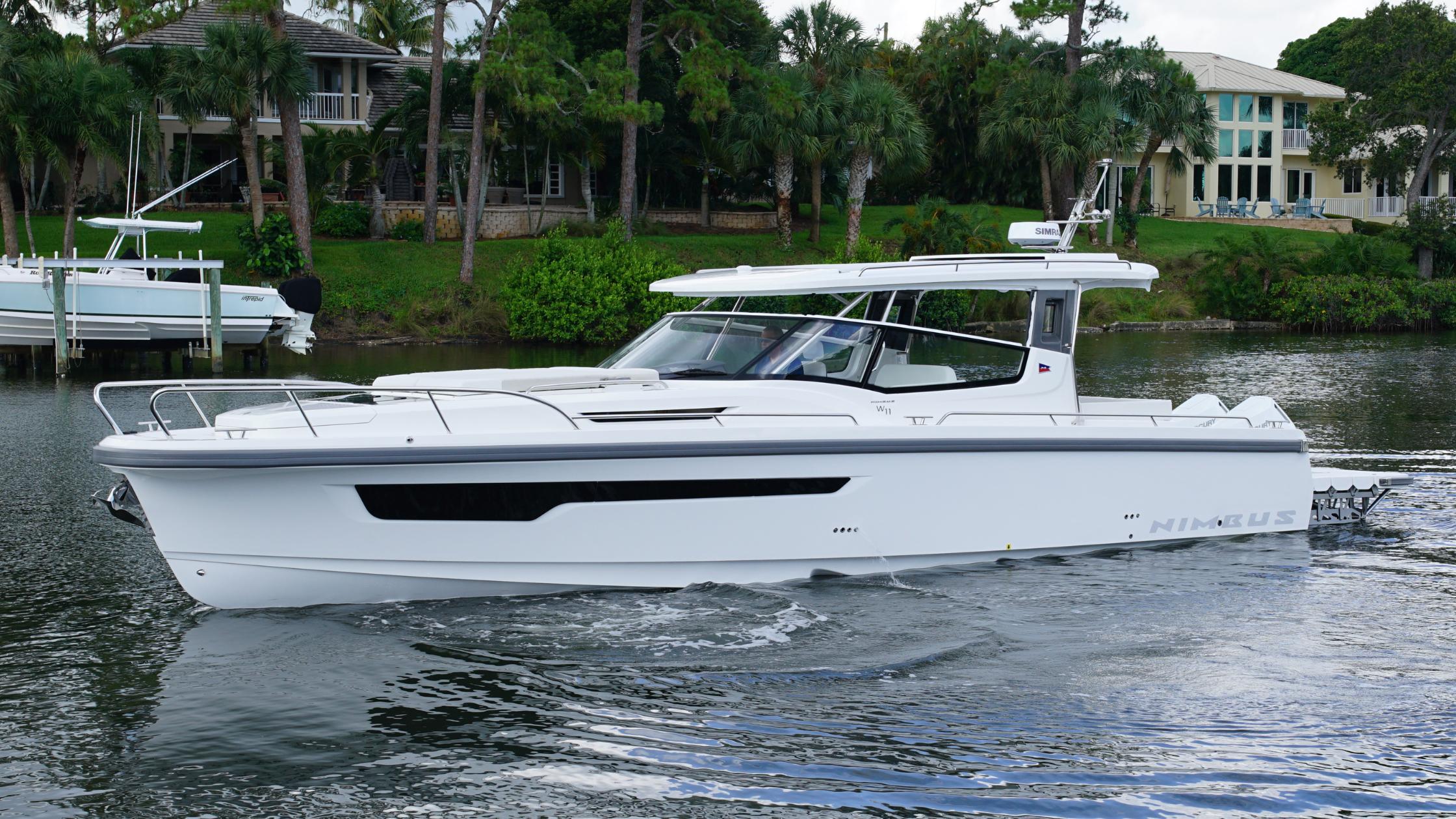 Nimbus-Weekender 11 #60 2025-In-Stock 2025 Nimbus W11 #60 FL-US-2025 Nimbus Weekender 11 #60 boat cruising on a calm river near lush greenery.-9829239