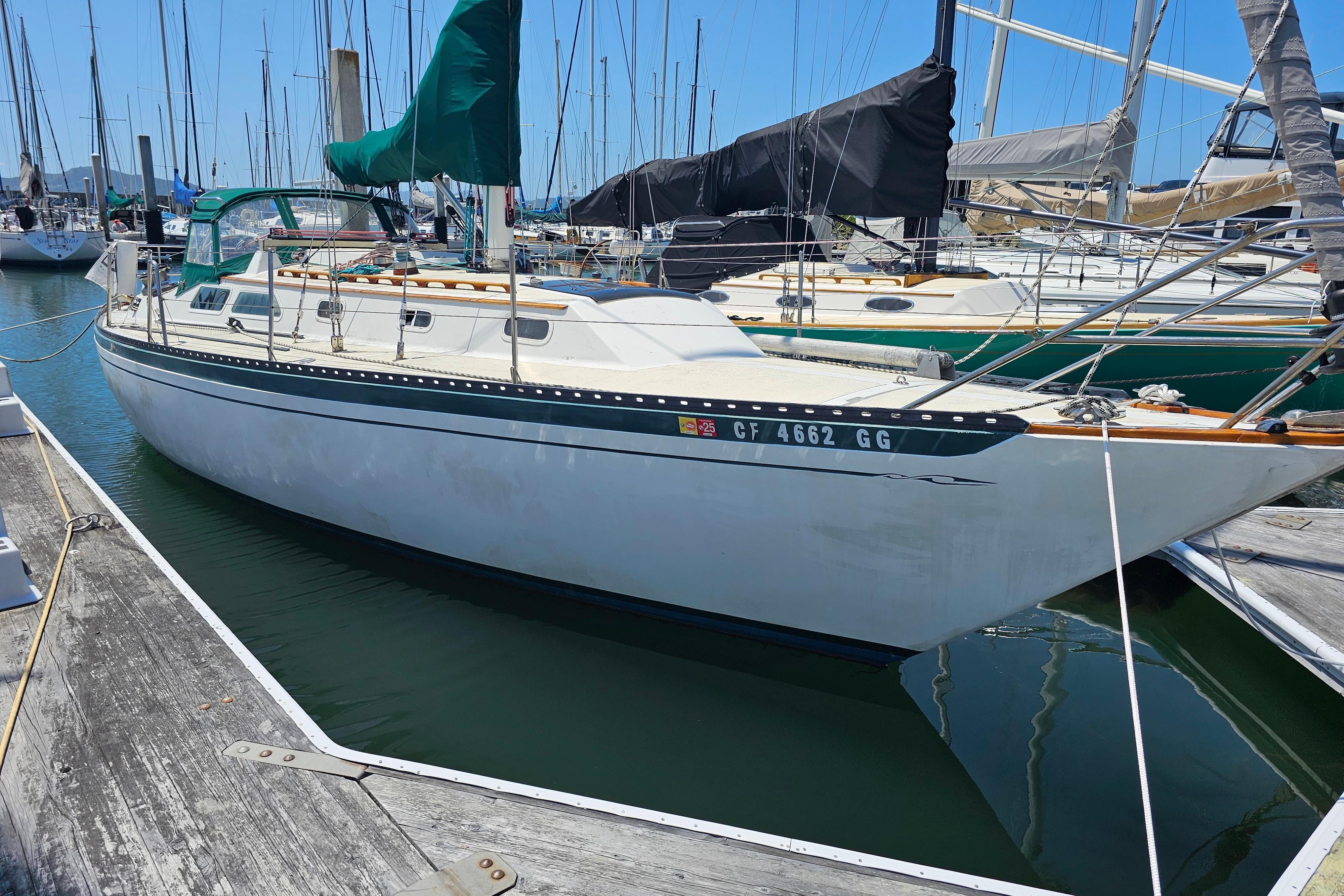 1978 Islander 36 sailboat docked in marina, featuring green sail cover.