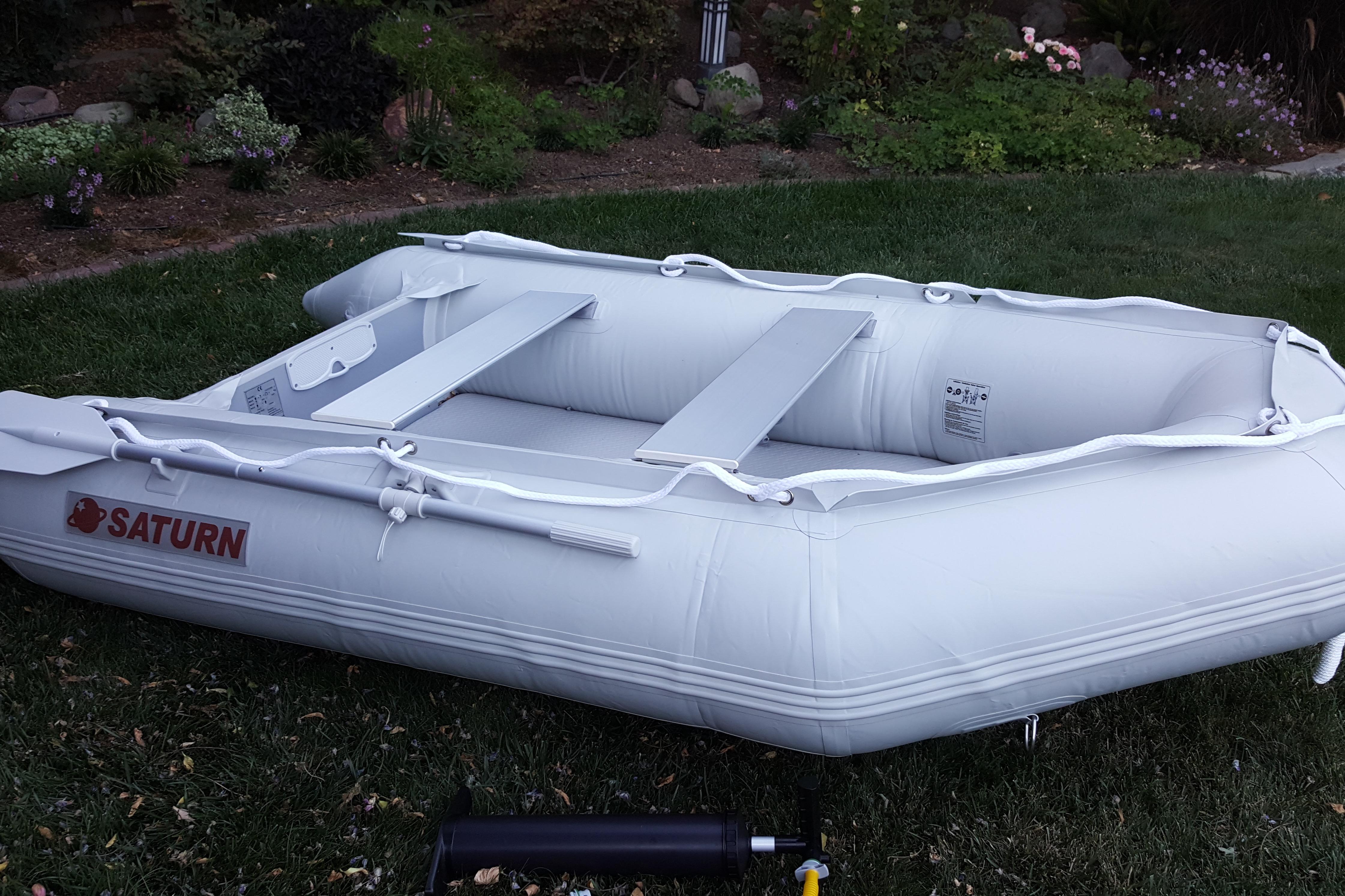 Inflatable Saturn boat on grass, featuring sturdy design and oars.