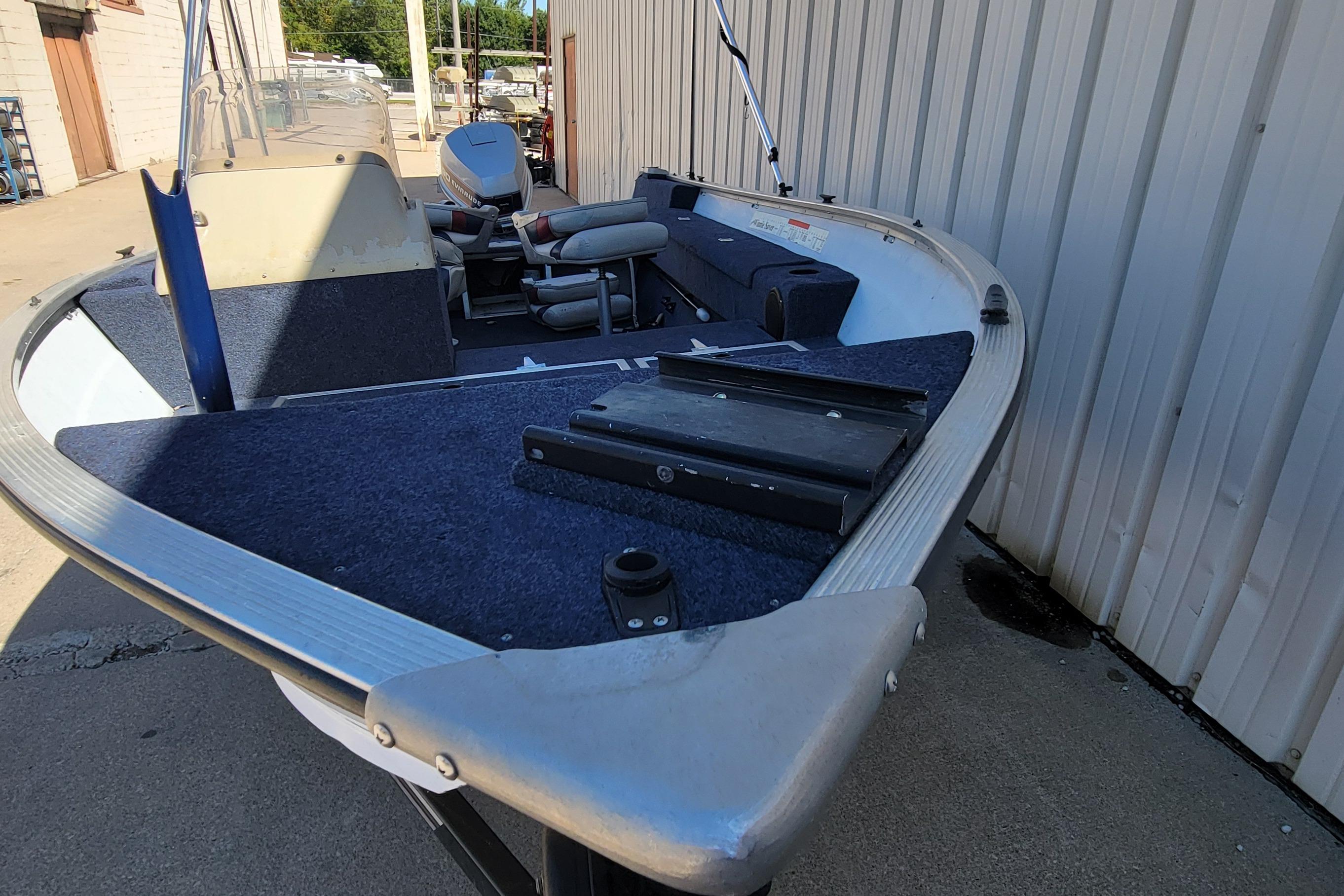 1997 Sea Nymph 168 DLX boat with blue interior, docked beside a building.