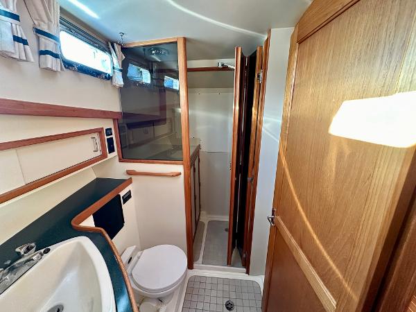 1997 Sabre Cockpit Motor Yacht bathroom with shower, sink, and wooden cabinetry.