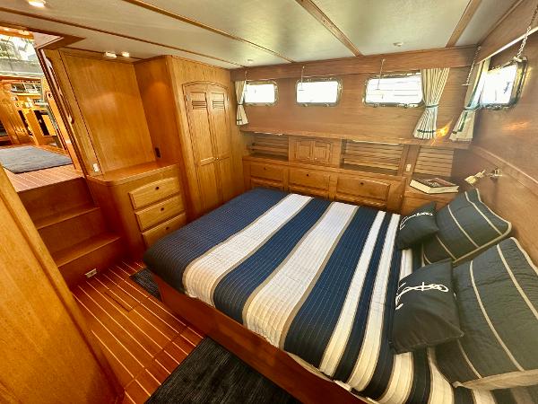 Luxurious 1997 Sabre Cockpit Motor Yacht bedroom with wood paneling and striped bedding.