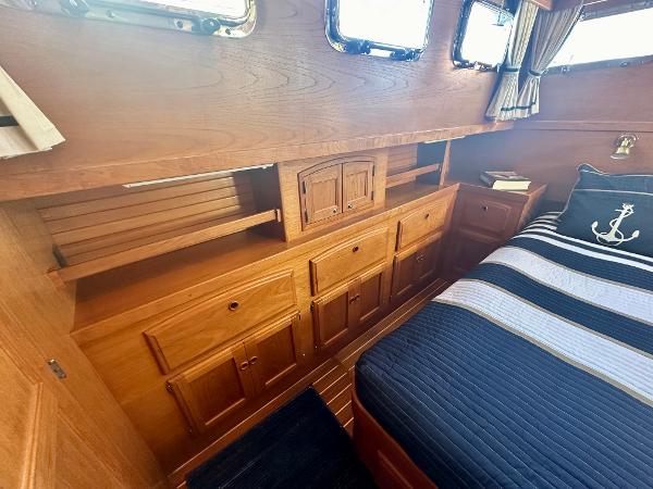 Interior of 1997 Sabre Cockpit Motor Yacht with wooden cabinetry and nautical-themed bedding.