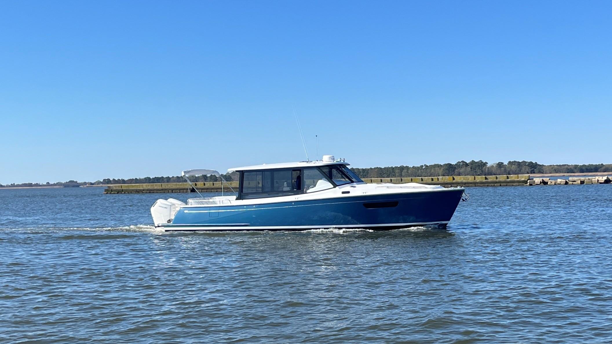 2025 MJM 4 boat cruising on a calm lake under a clear blue sky.