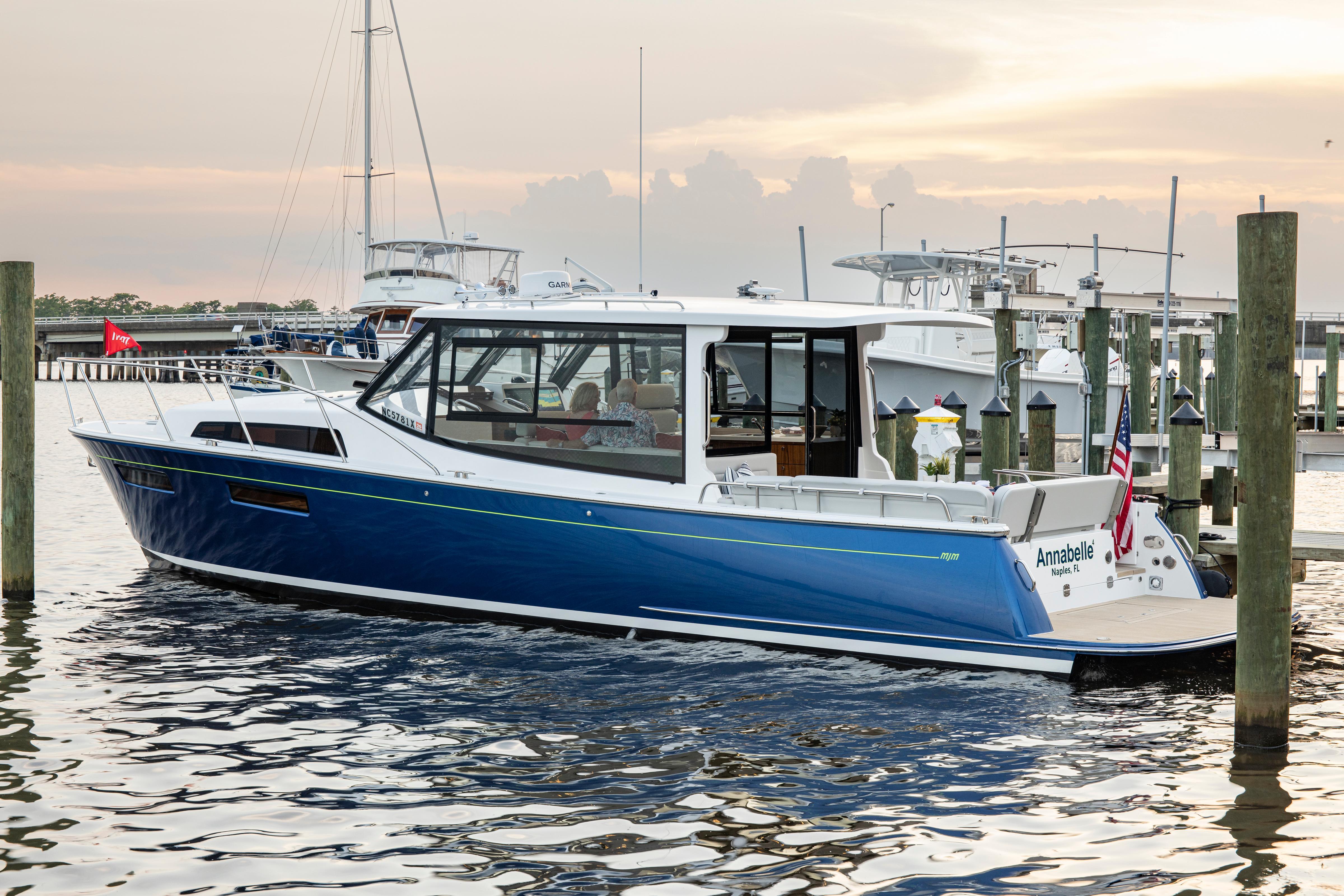 2025 MJM 42 yacht docked at marina during sunset, featuring sleek blue design.