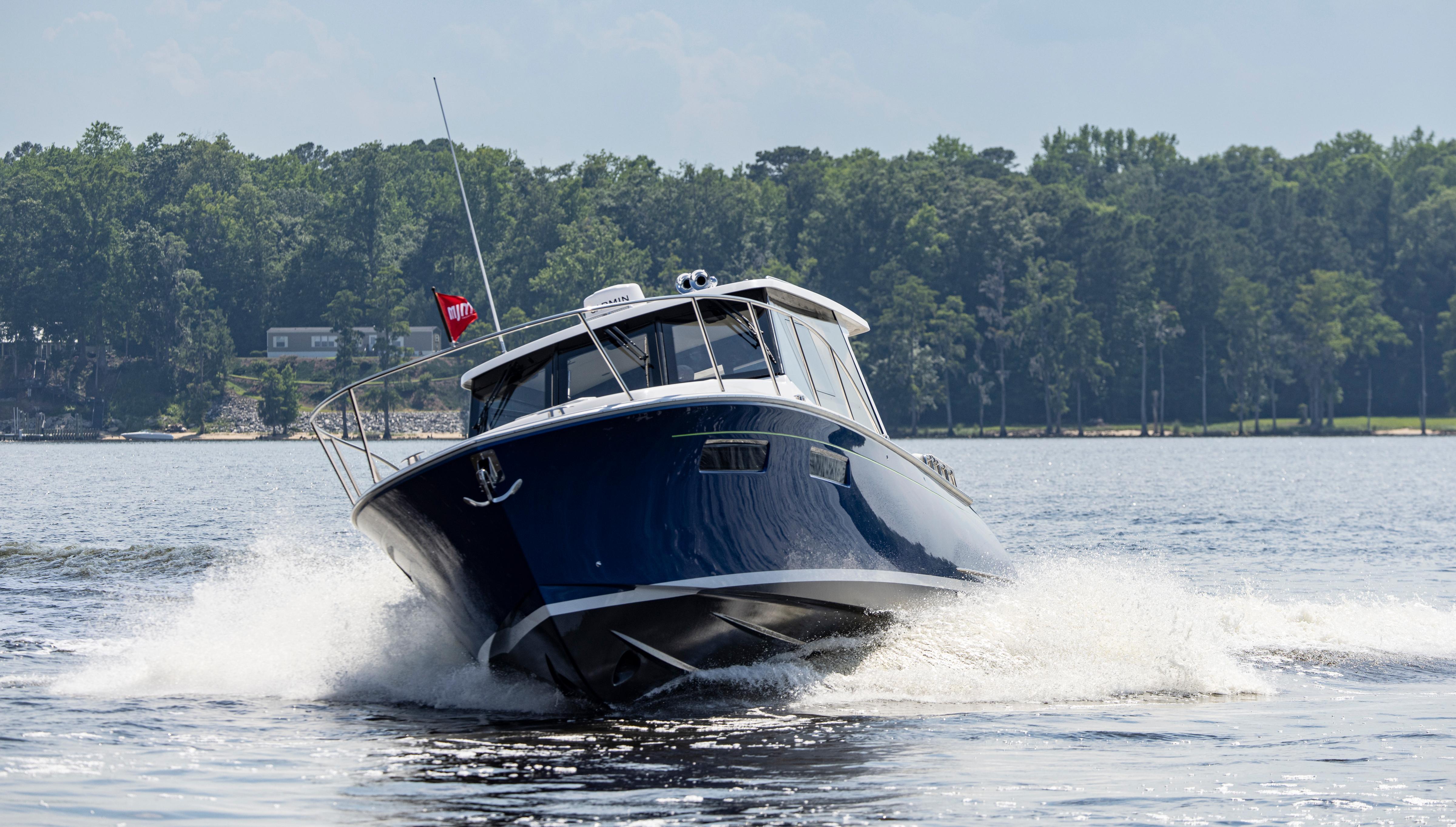 2025 MJM 42 boat cruising on a lake with forested shoreline.
