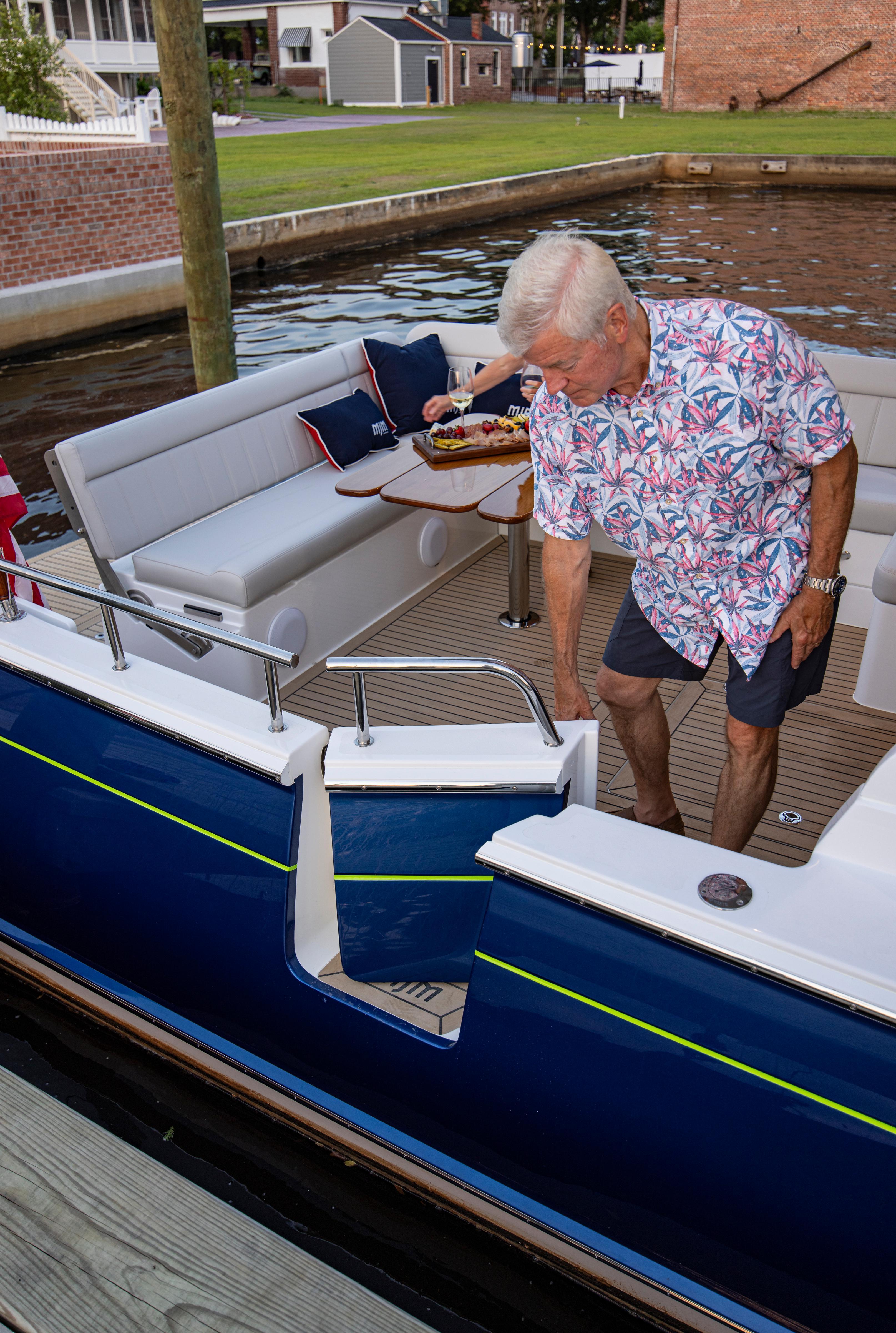 Man boarding a 2025 MJM 42 yacht, featuring a stylish deck and seating area.