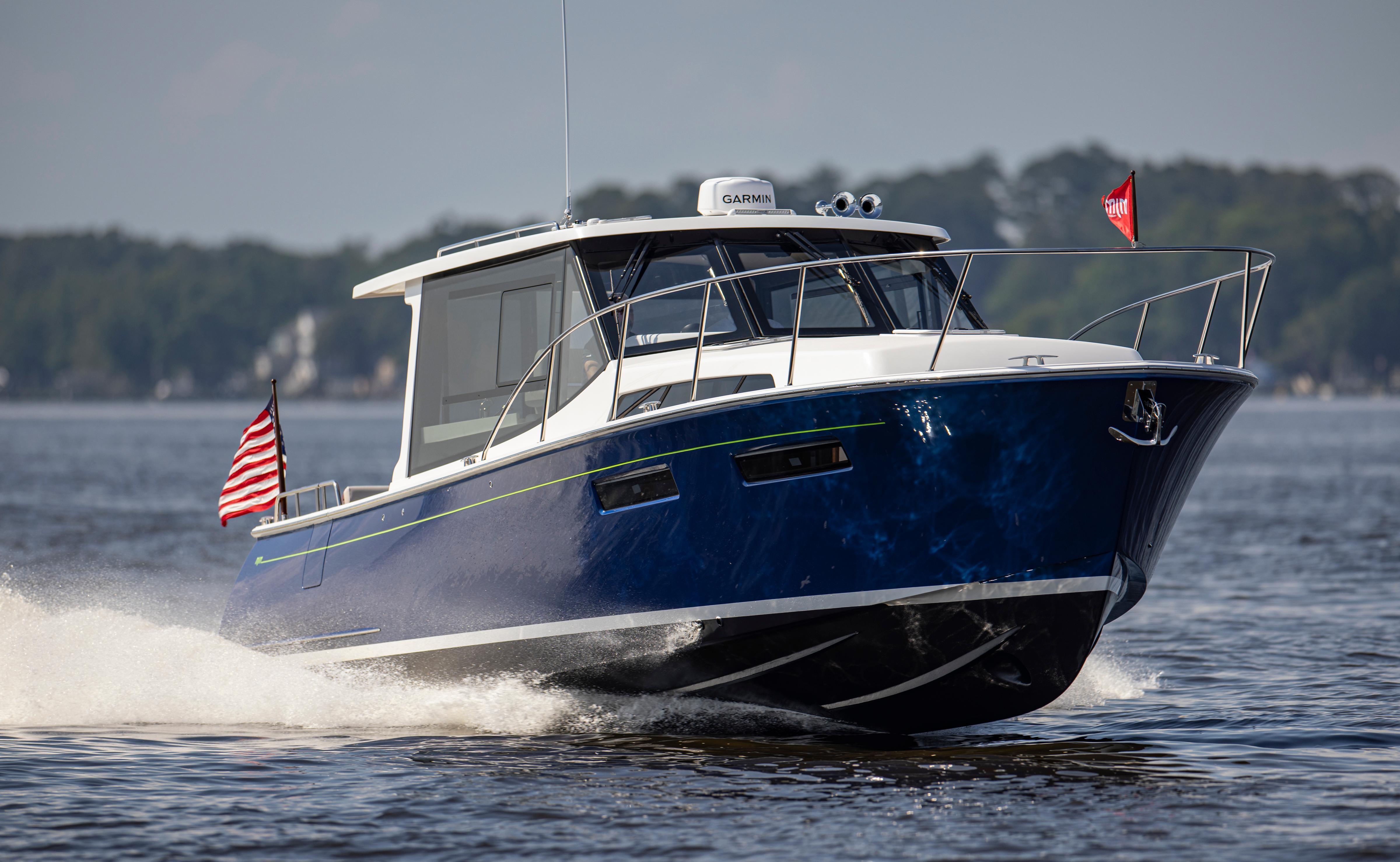 2025 MJM 42 boat cruising on water with American flag, blue hull, and Garmin equipment.