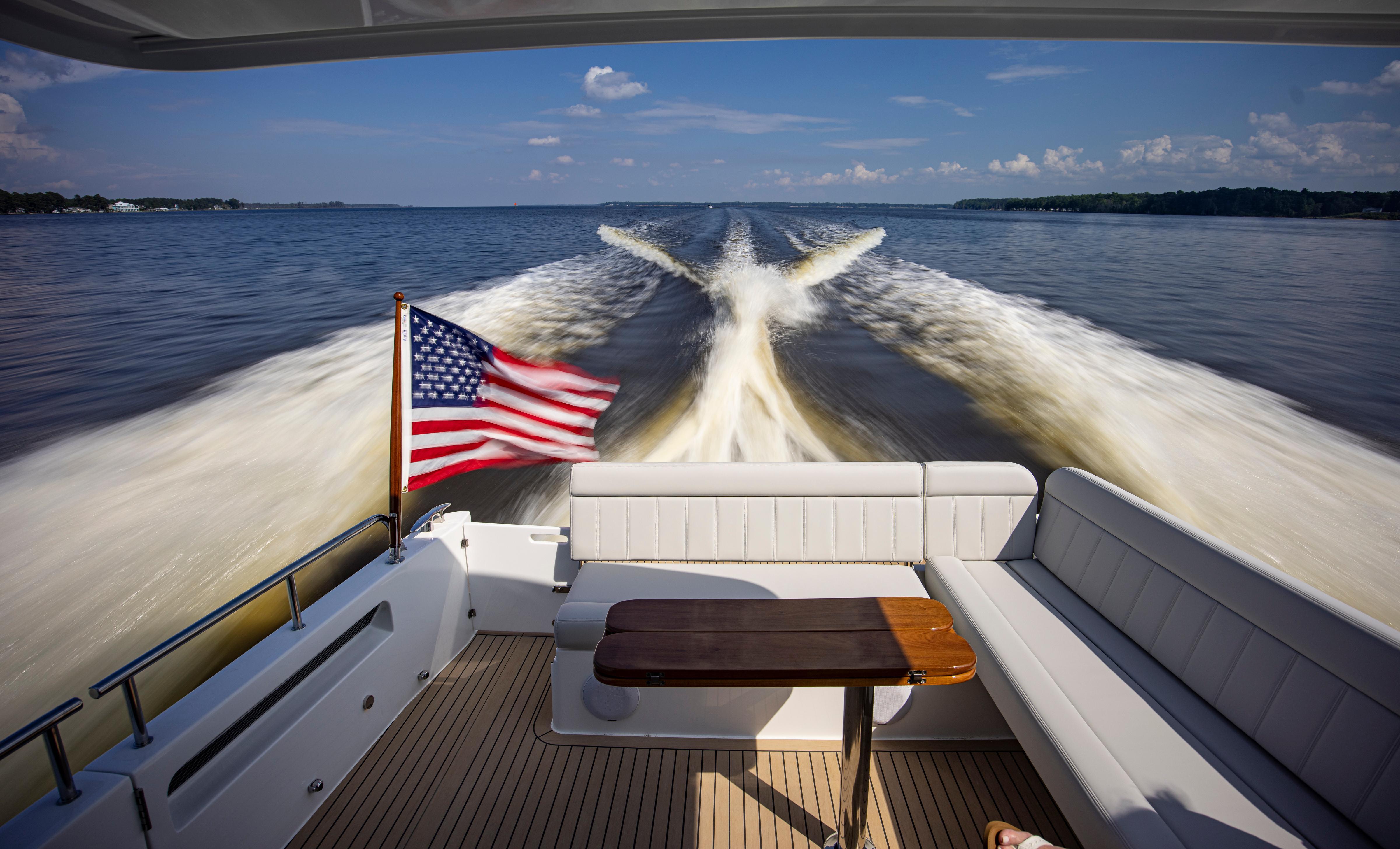 2025 MJM 42 yacht cruising with American flag, leaving wake on open water.