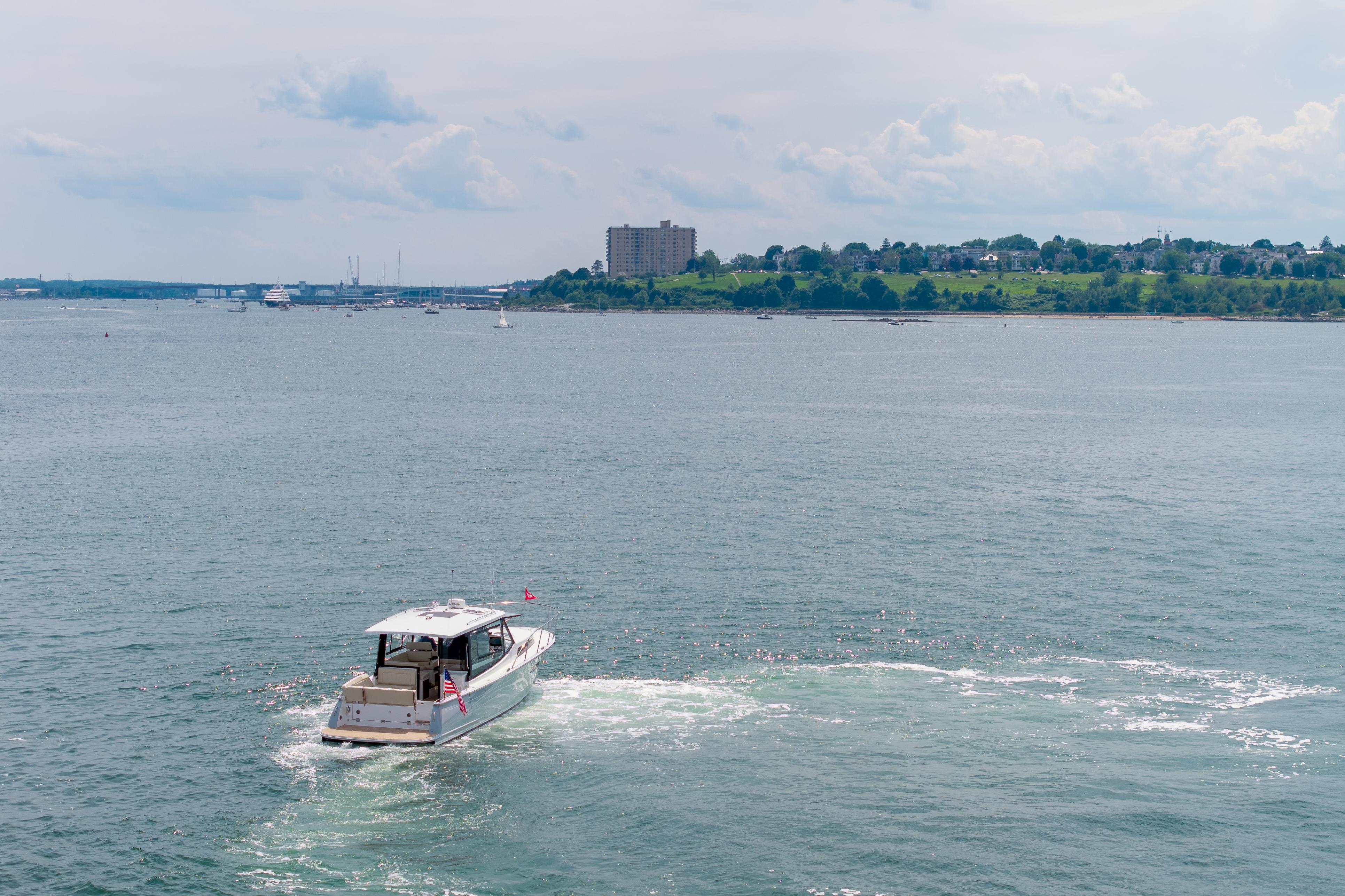 A 2025 MJM 42 boat cruising on a calm sea near a distant shoreline.