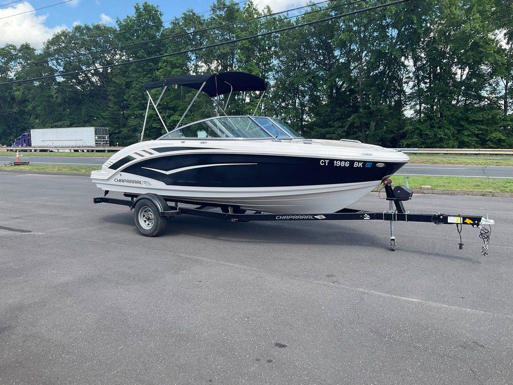 2018 Chaparral 203 VR boat on trailer, parked on asphalt near trees.