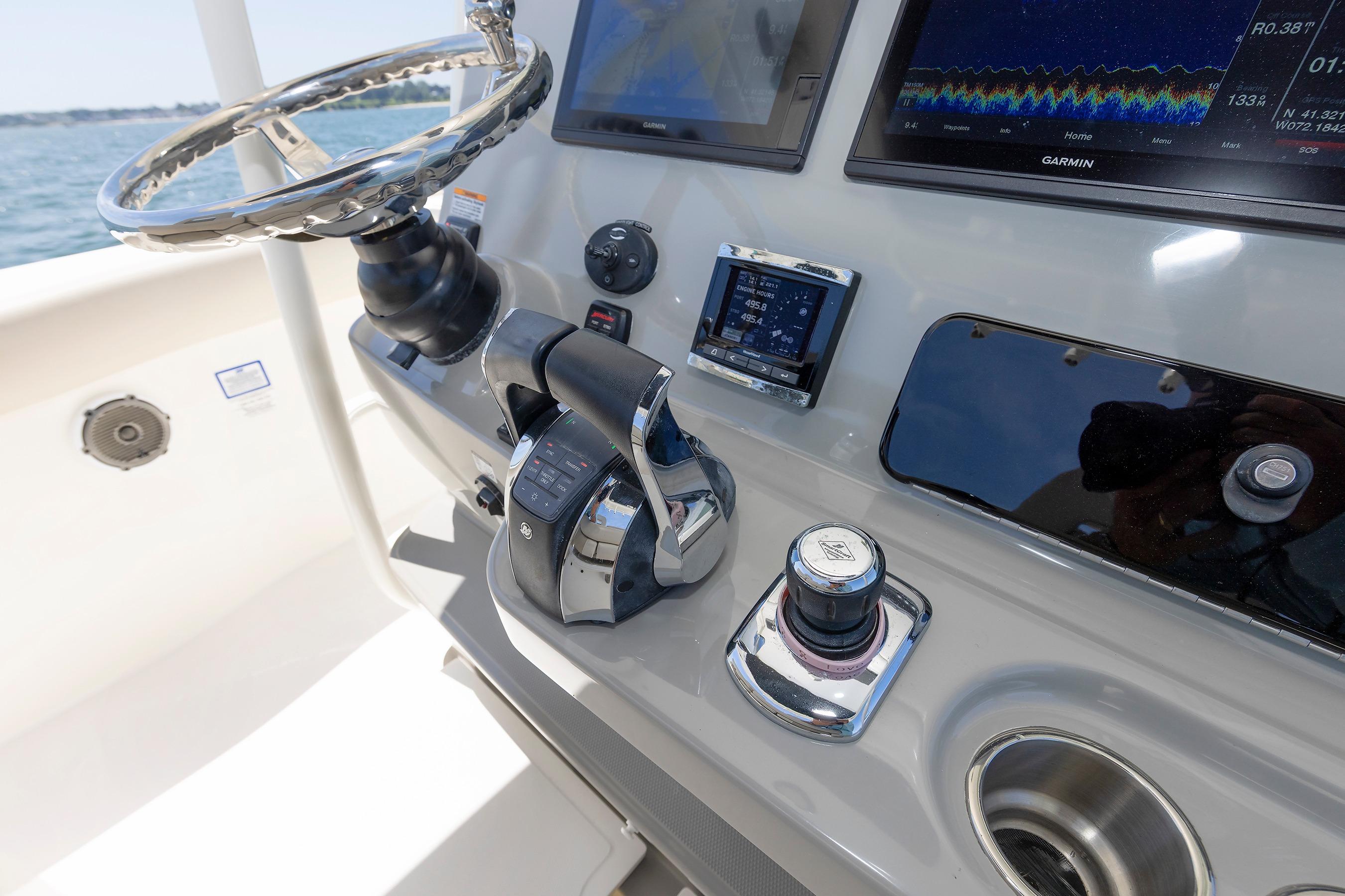 Control panel of a 2016 Boston Whaler 330 Outrage boat with steering wheel and navigation screens.