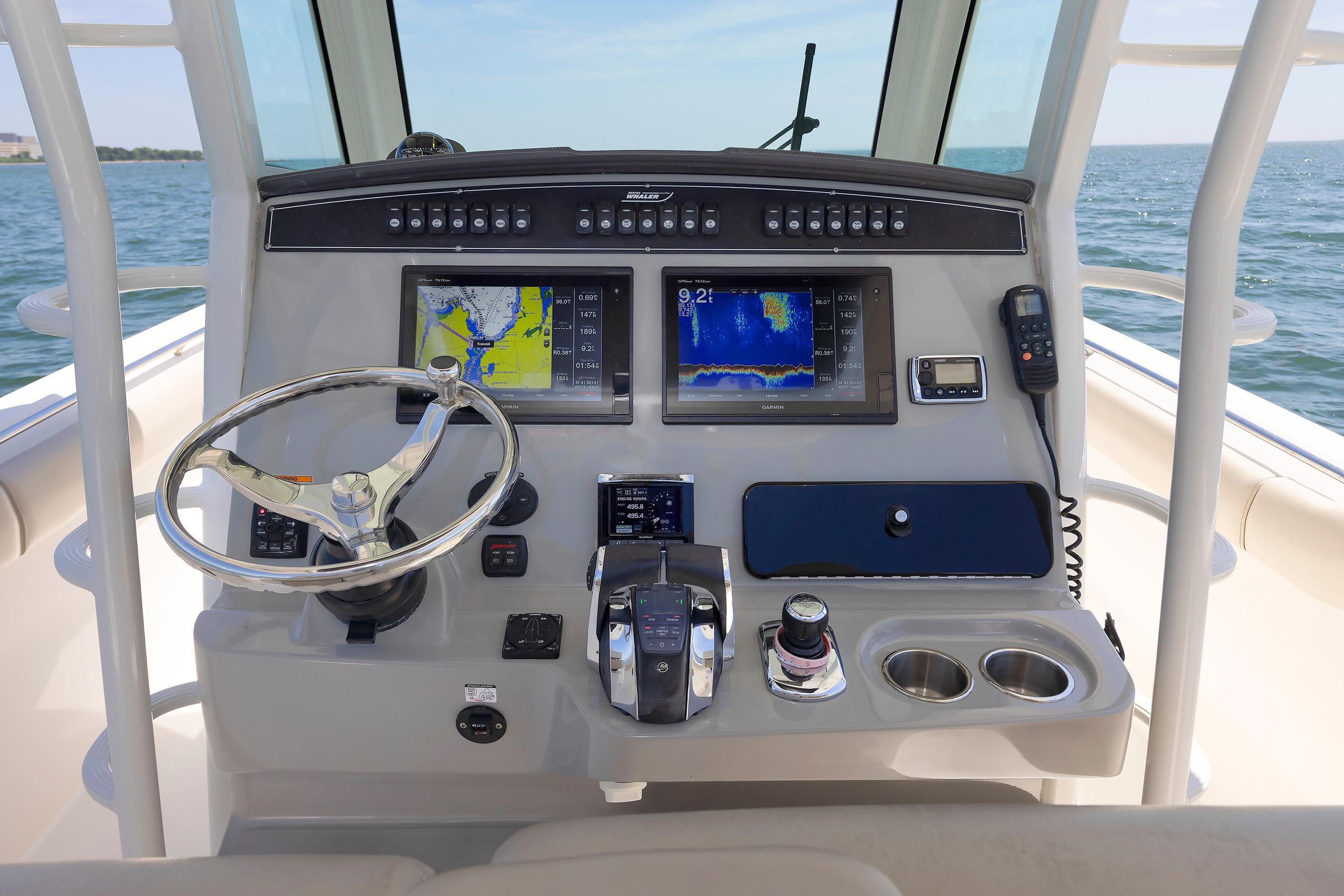 Control panel of 2016 Boston Whaler 330 Outrage with navigation screens and steering wheel.