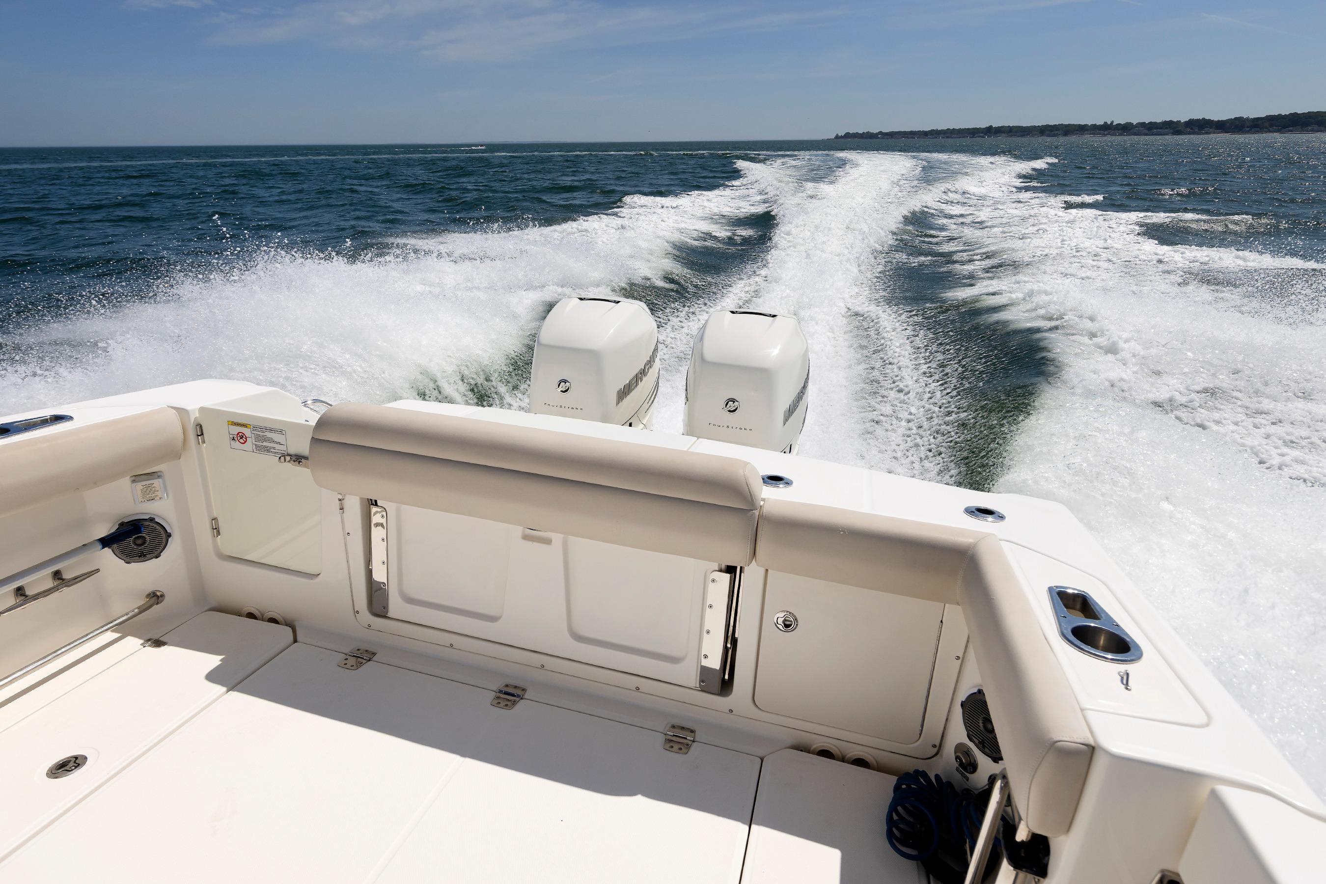 2016 Boston Whaler 330 Outrage cruising on open water, rear view with twin engines.