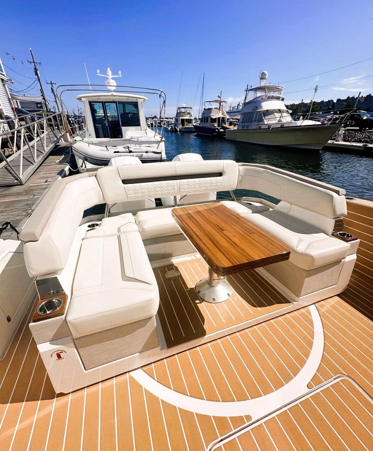 2024 Tiara Yachts 43 LS with elegant seating and wooden table at a marina.