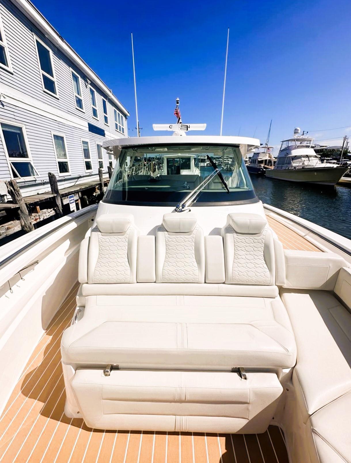 2024 Tiara Yachts 43 LS luxury boat with plush seating, docked near waterfront buildings.