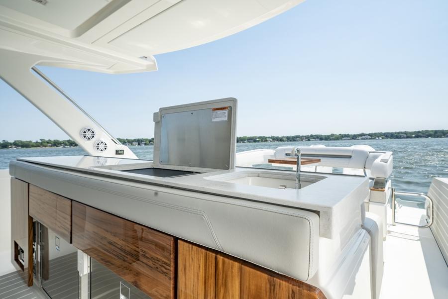 2024 Tiara Yachts 43 LS outdoor kitchen with sink and grill, overlooking serene waters.
