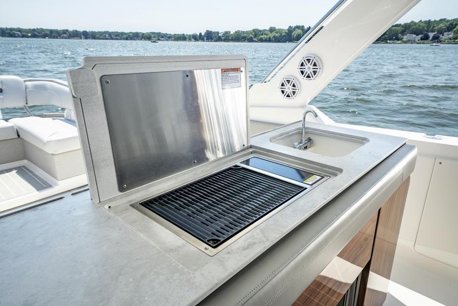 Outdoor kitchen on 2024 Tiara Yachts 43 LS, featuring grill and sink by the water.