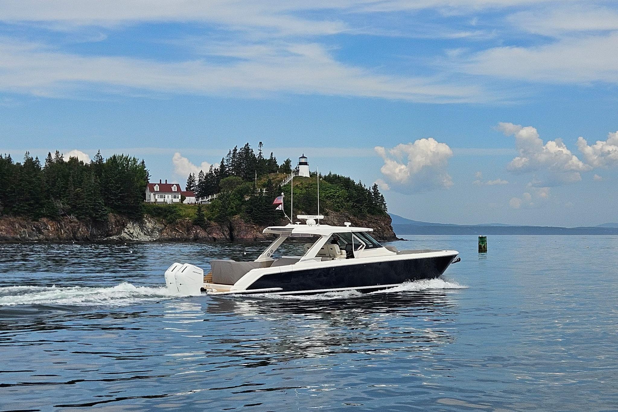 2024 Tiara Yachts 43 LS cruising near a scenic coastal lighthouse.
