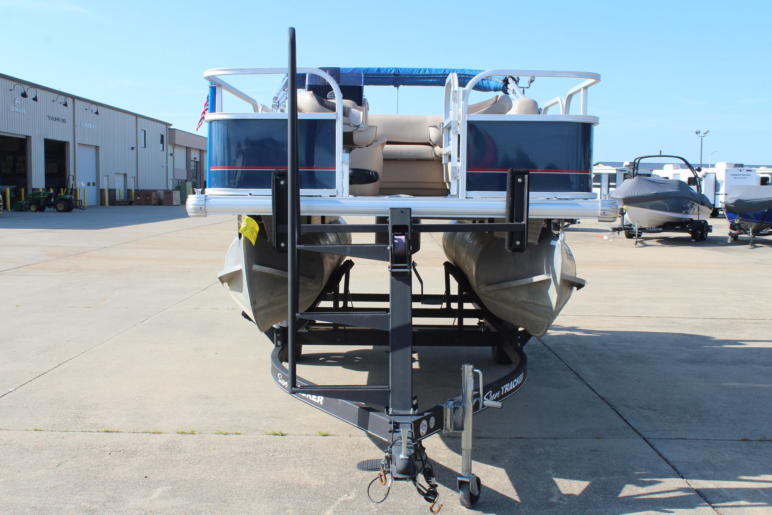 2019 Sun Tracker Bass Buggy 16 XL Select pontoon boat on trailer in a marina.