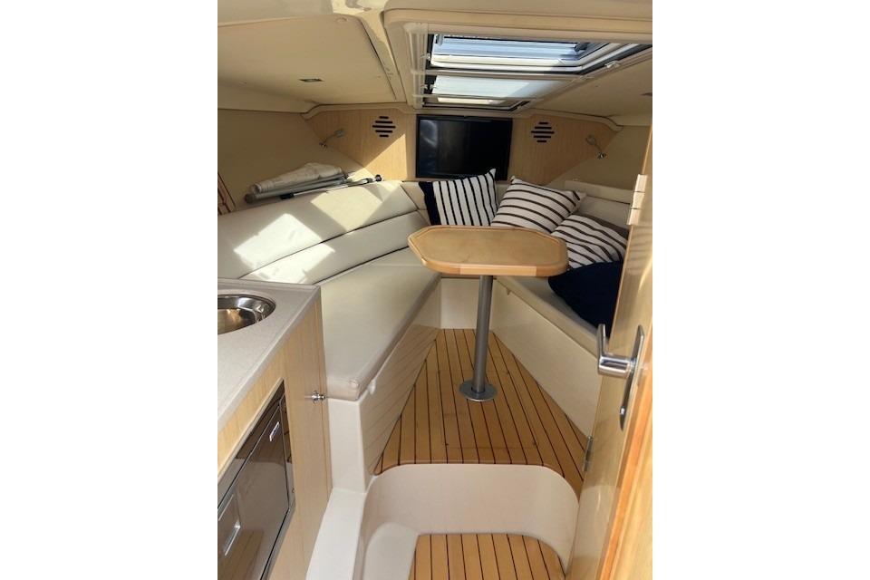 2017 Chris-Craft Corsair 32 cabin interior with seating, table, and striped cushions.