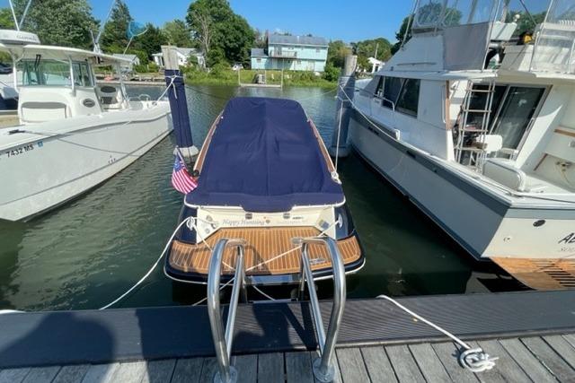 2017 Chris-Craft Corsair 32 docked between boats, covered with a navy blue tarp.