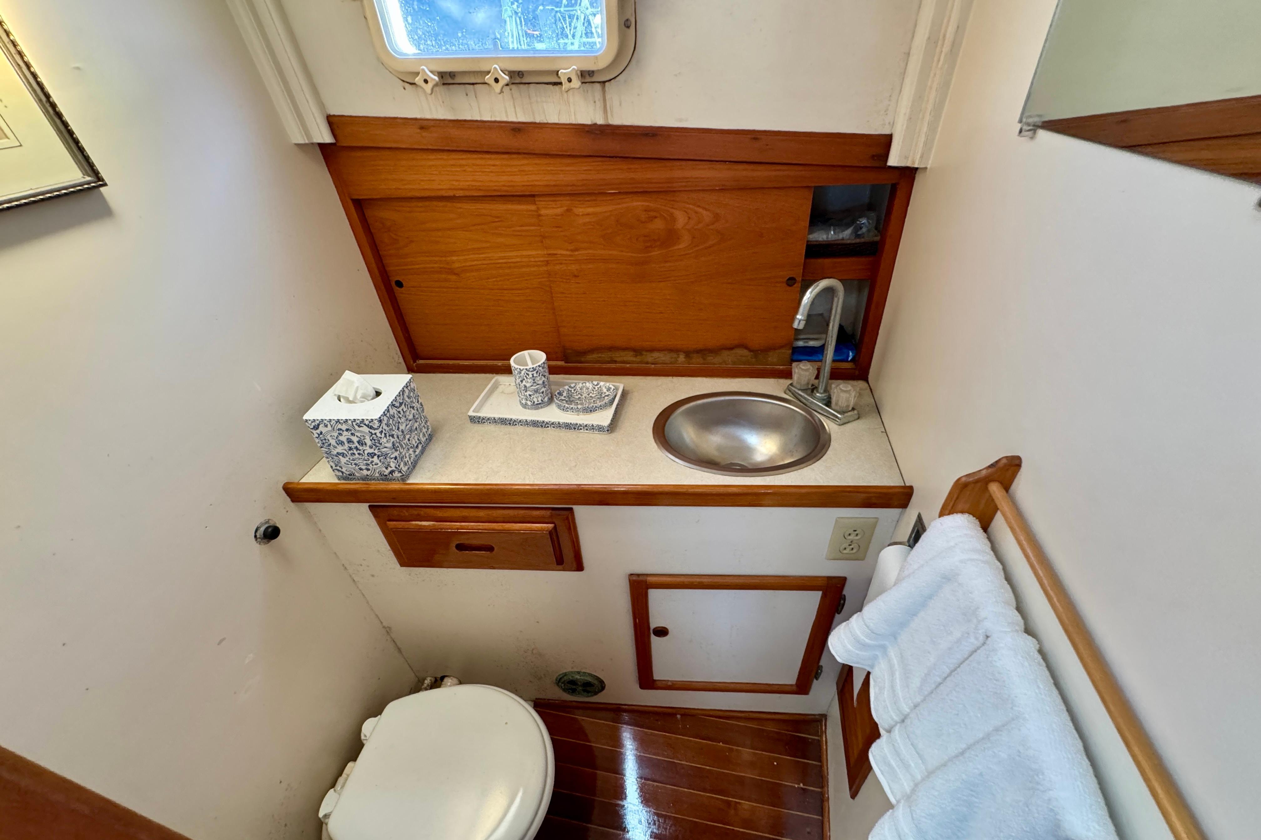 1982 Jarvis Newman Flybridge Cruiser bathroom with sink, toilet, and wooden cabinetry.