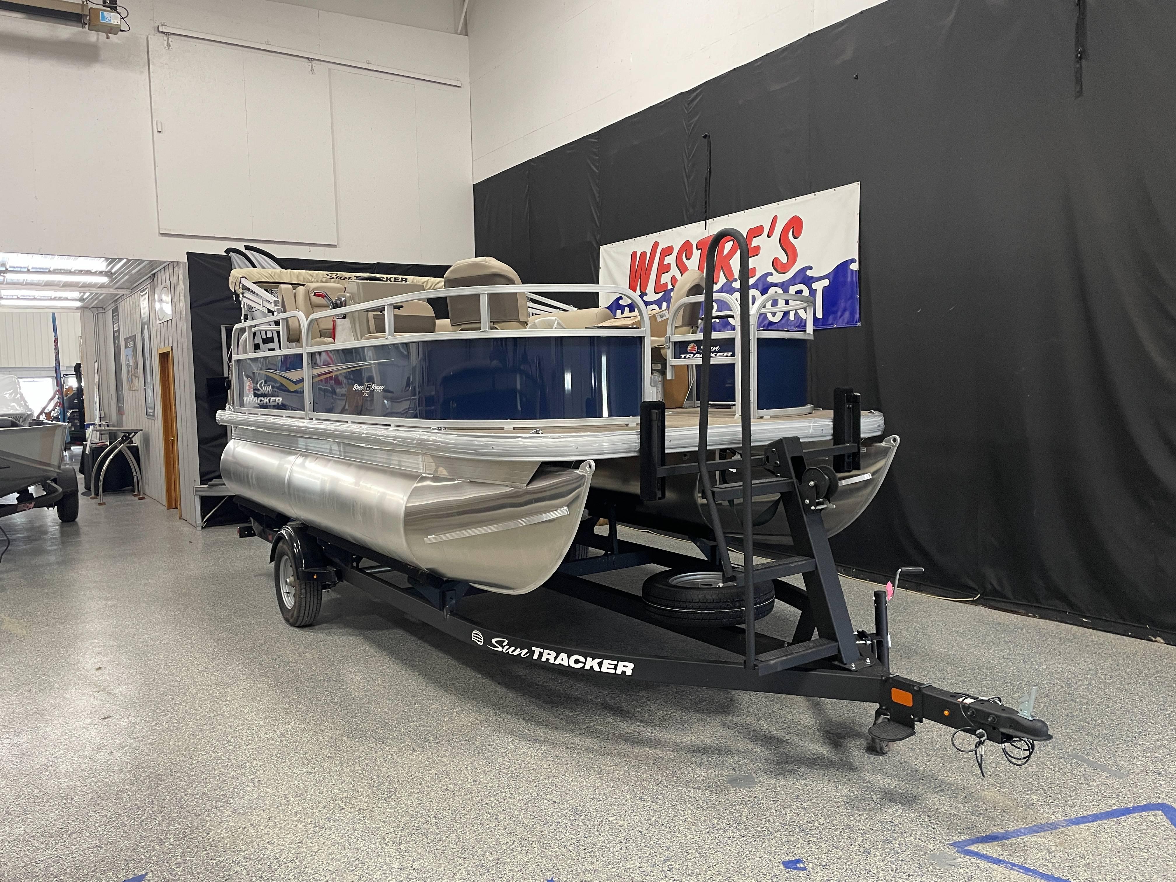 2025 Sun Tracker Bass Buggy 16 XL Select pontoon boat on trailer in showroom.