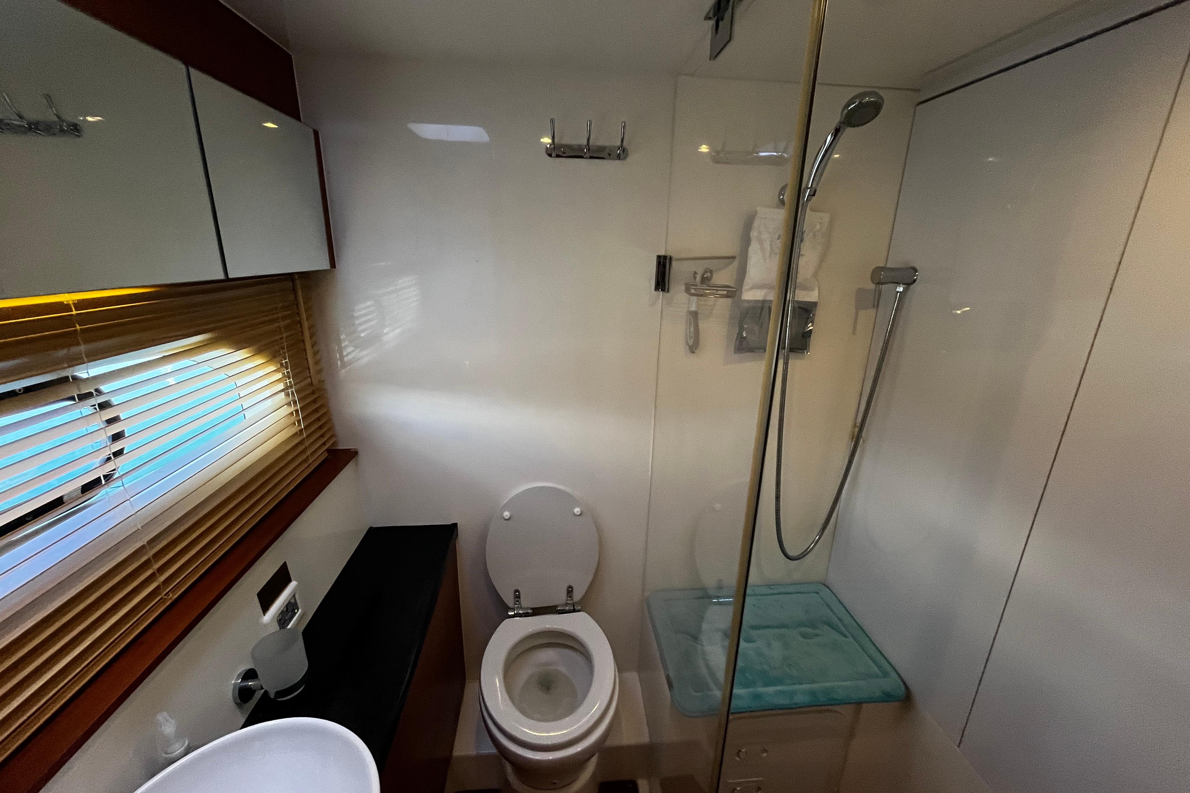Modern bathroom in 2016 Aquila 44 yacht with shower, toilet, and window blinds.