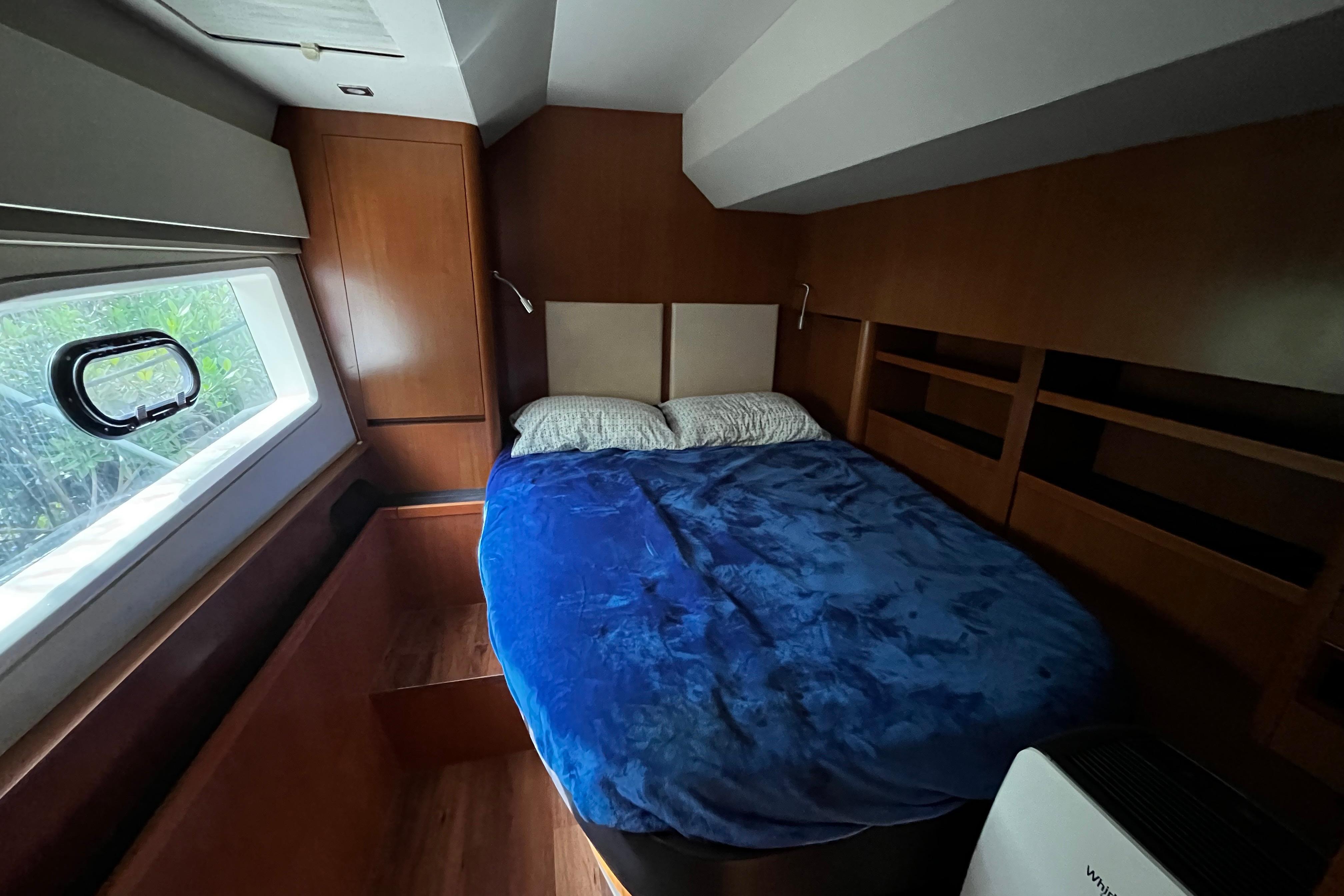 Cozy bedroom in 2016 Aquila 44 yacht with blue bedding and wooden interior.