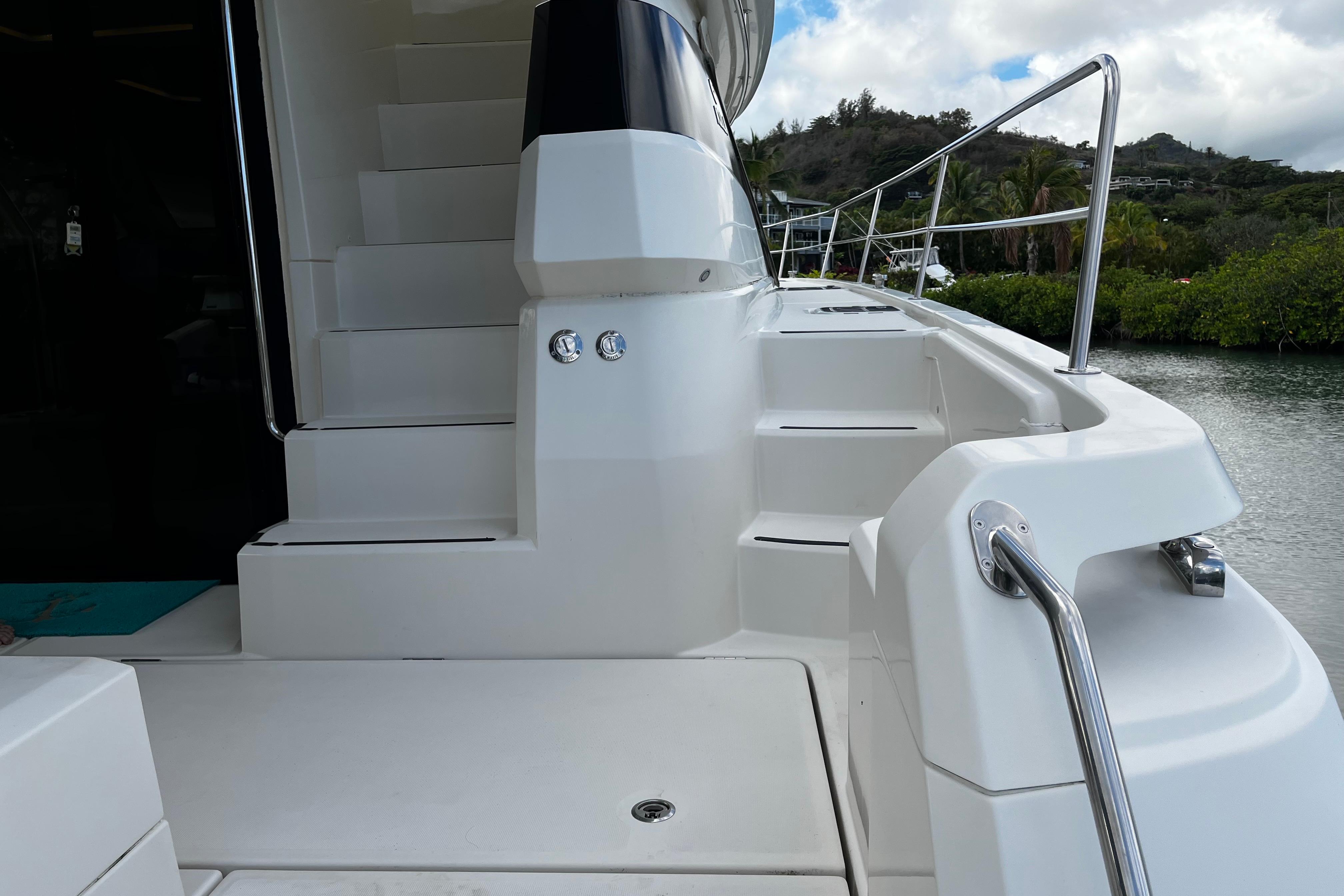 Staircase on 2016 Aquila 44 yacht, featuring sleek white design and stainless steel railings.