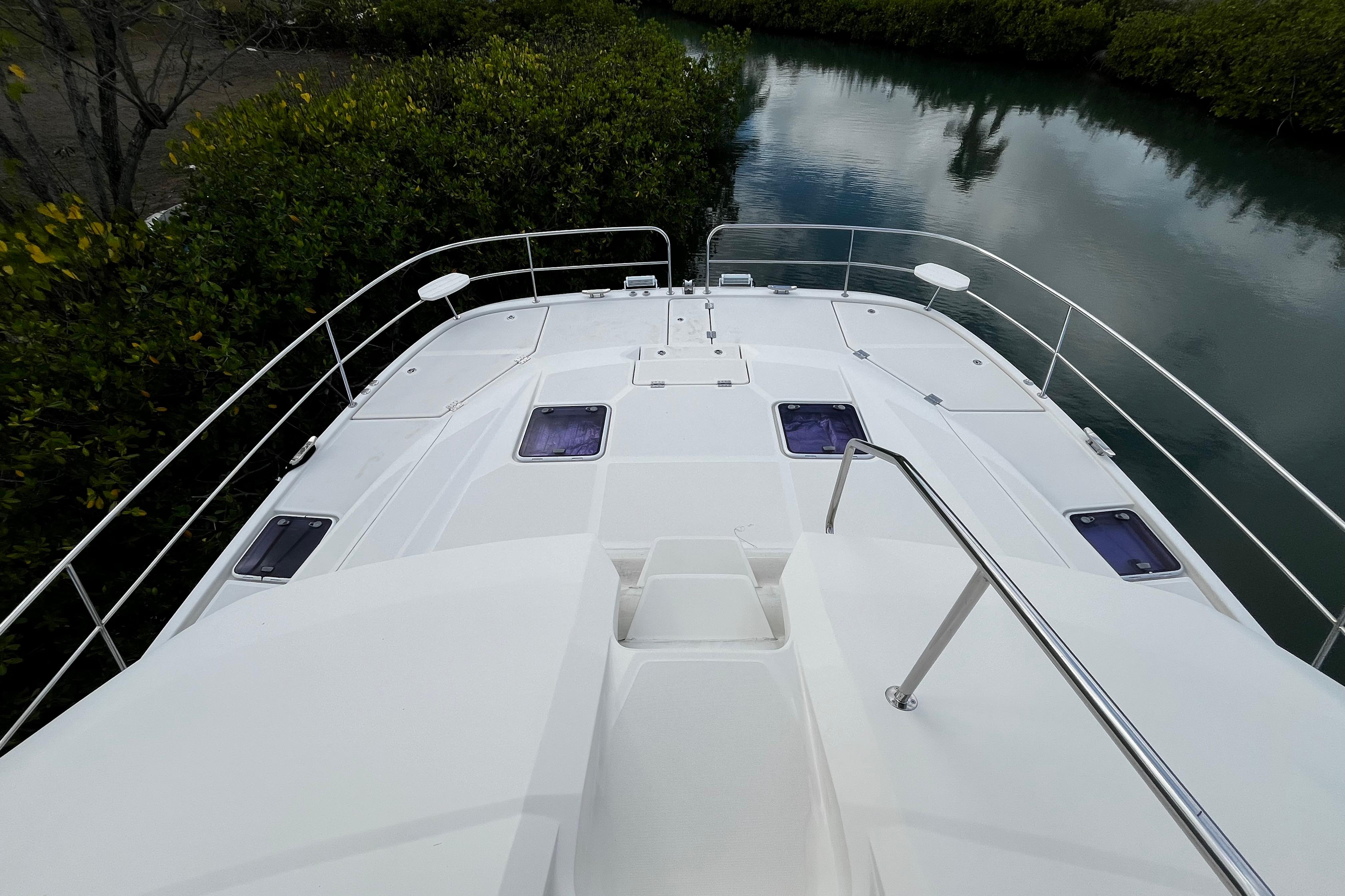 Aquila 44 yacht deck, 2016 model, overlooking serene waterway and lush greenery.