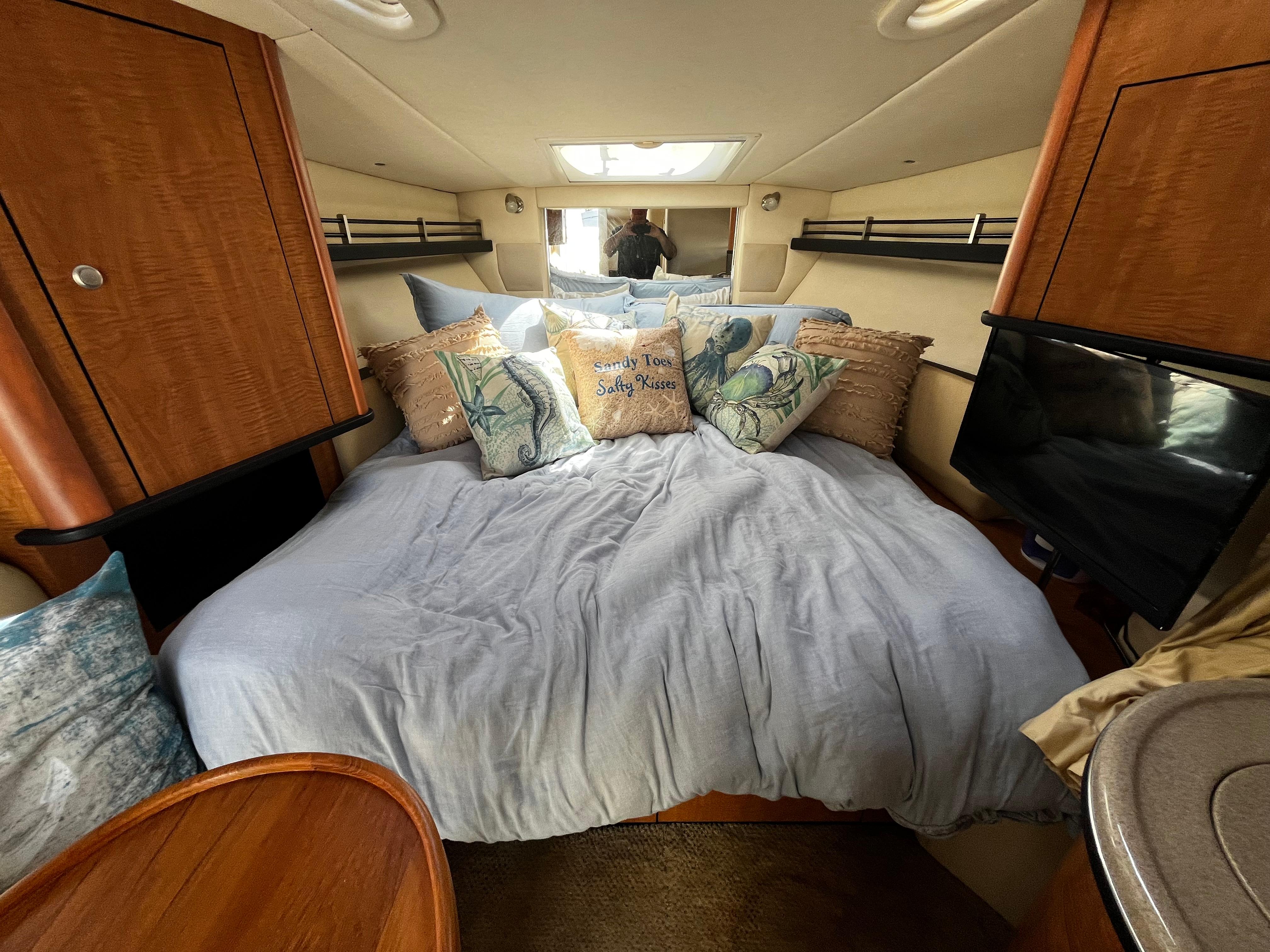 Cozy cabin interior of 2006 Sea Ray 290 Sundancer with plush bedding and decorative pillows.