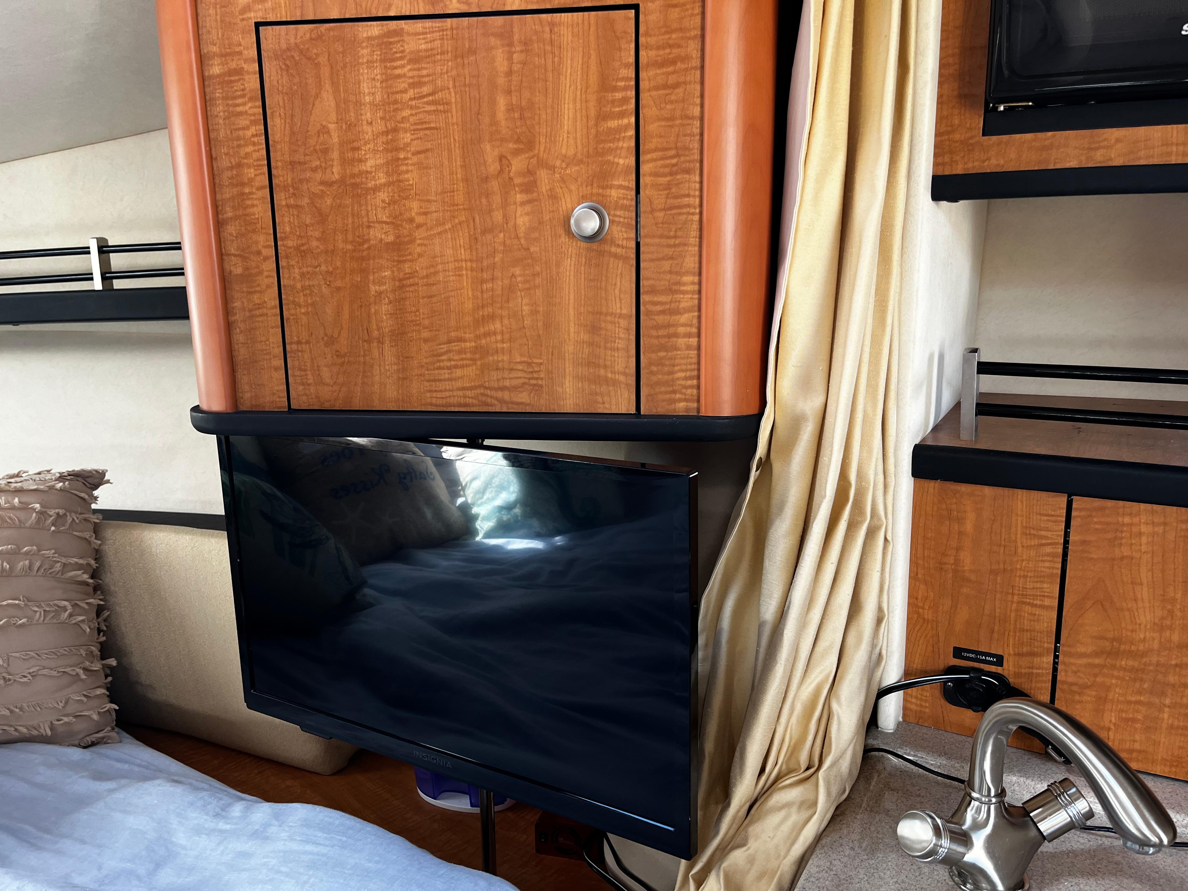 Interior of 2006 Sea Ray 290 Sundancer with TV, wooden cabinetry, and modern faucet.
