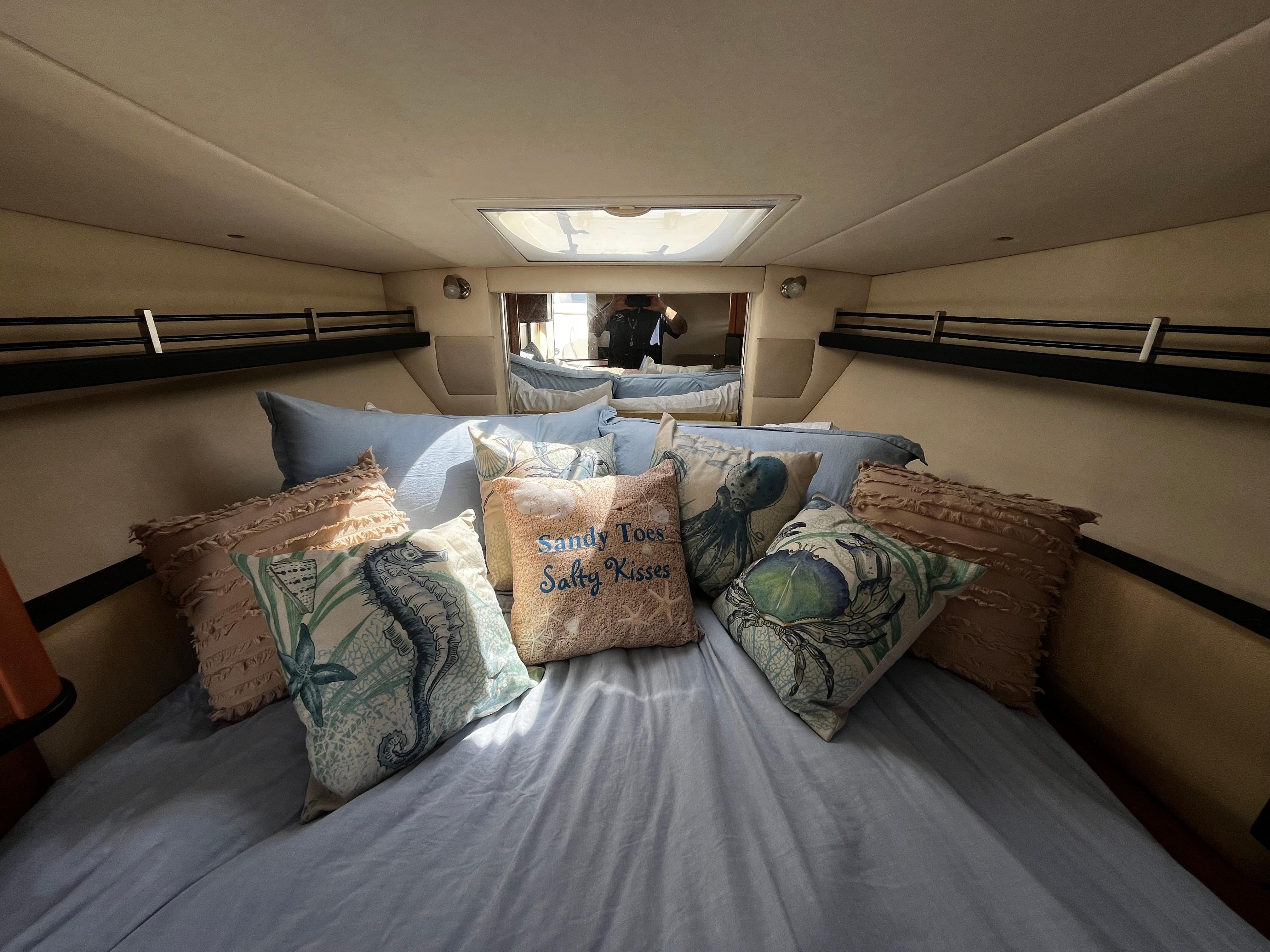 Cozy cabin interior of 2006 Sea Ray 290 Sundancer with nautical-themed pillows.