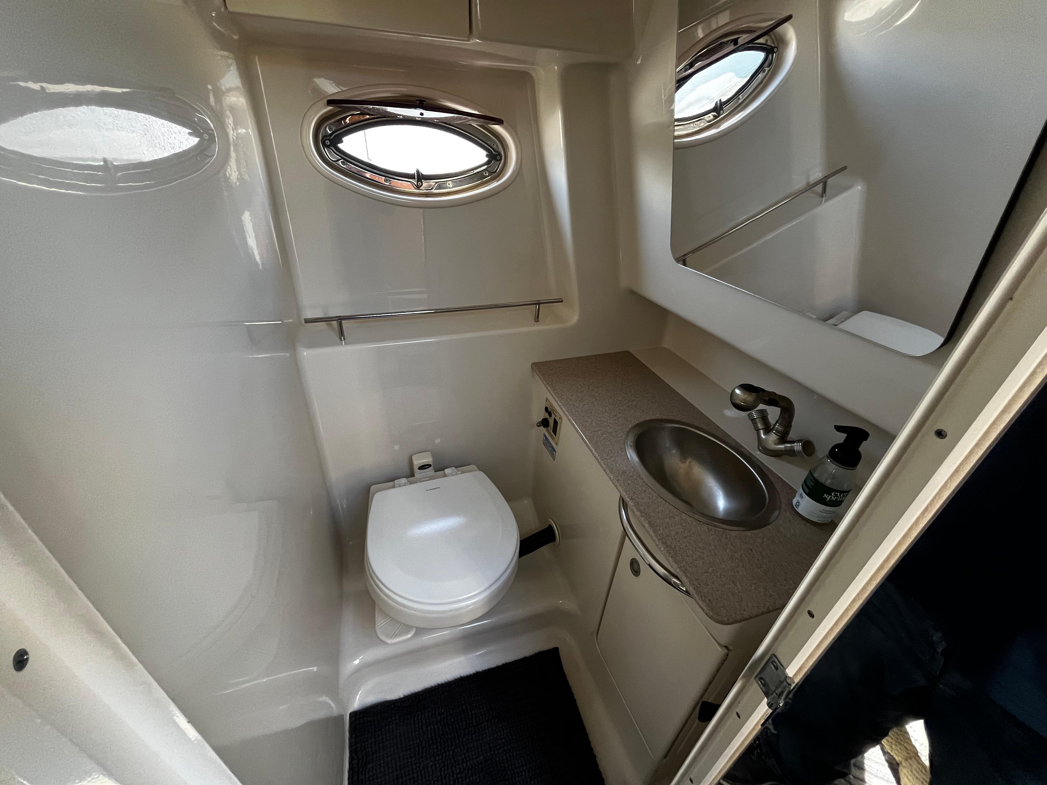 2006 Sea Ray 290 Sundancer bathroom with toilet, sink, and porthole window.