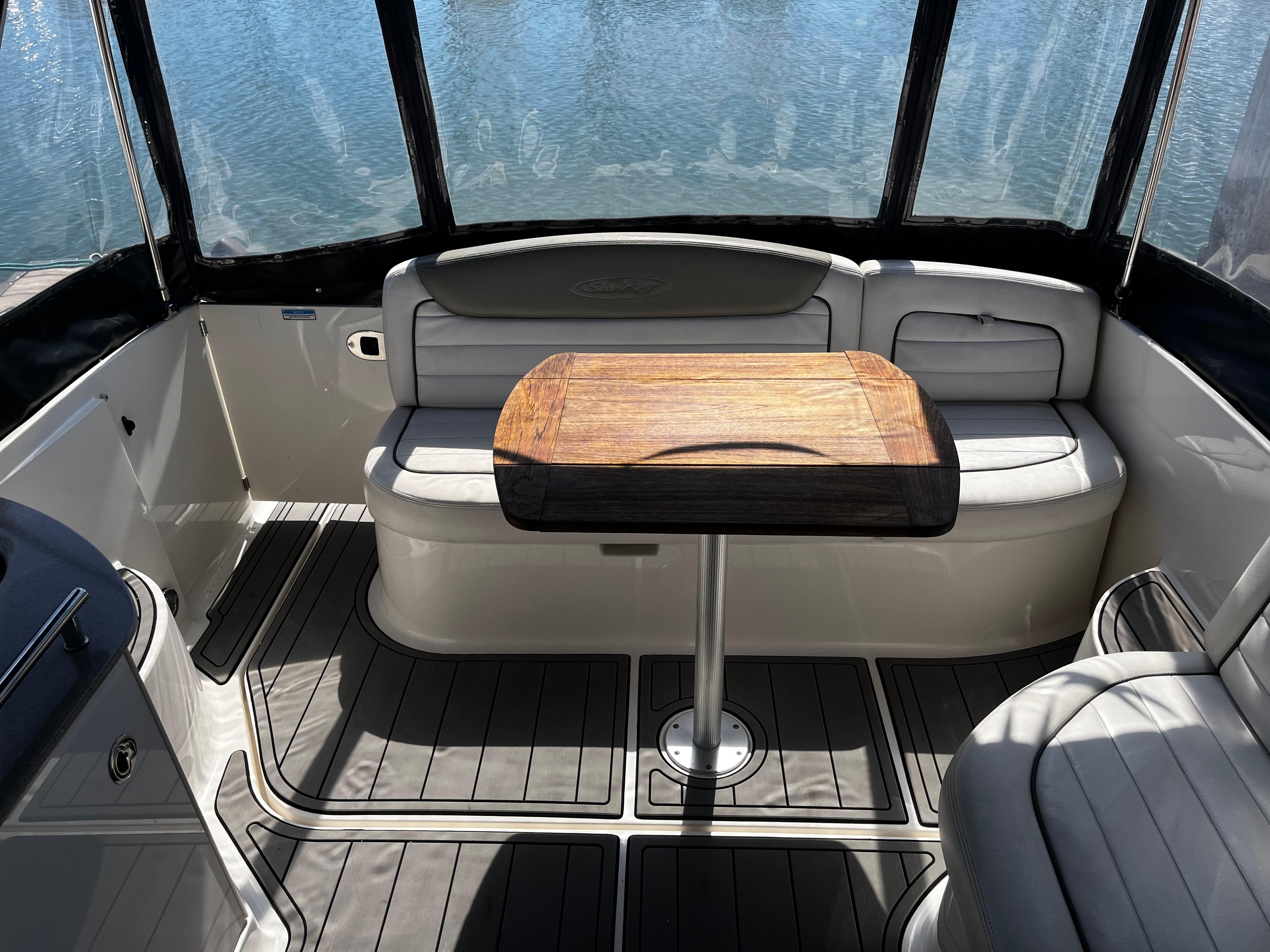 2006 Sea Ray 290 Sundancer interior with seating and wooden table, overlooking water.