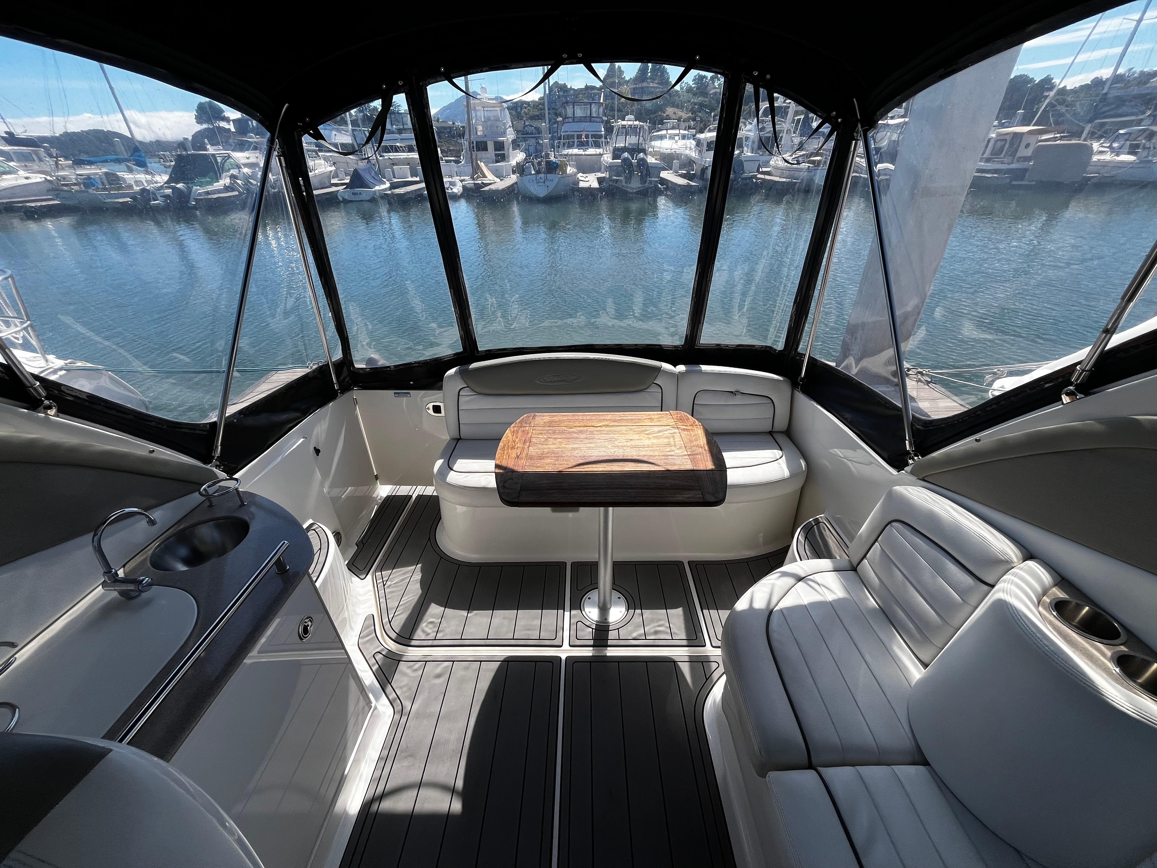 Interior of 2006 Sea Ray 290 Sundancer boat with seating and table, docked at marina.