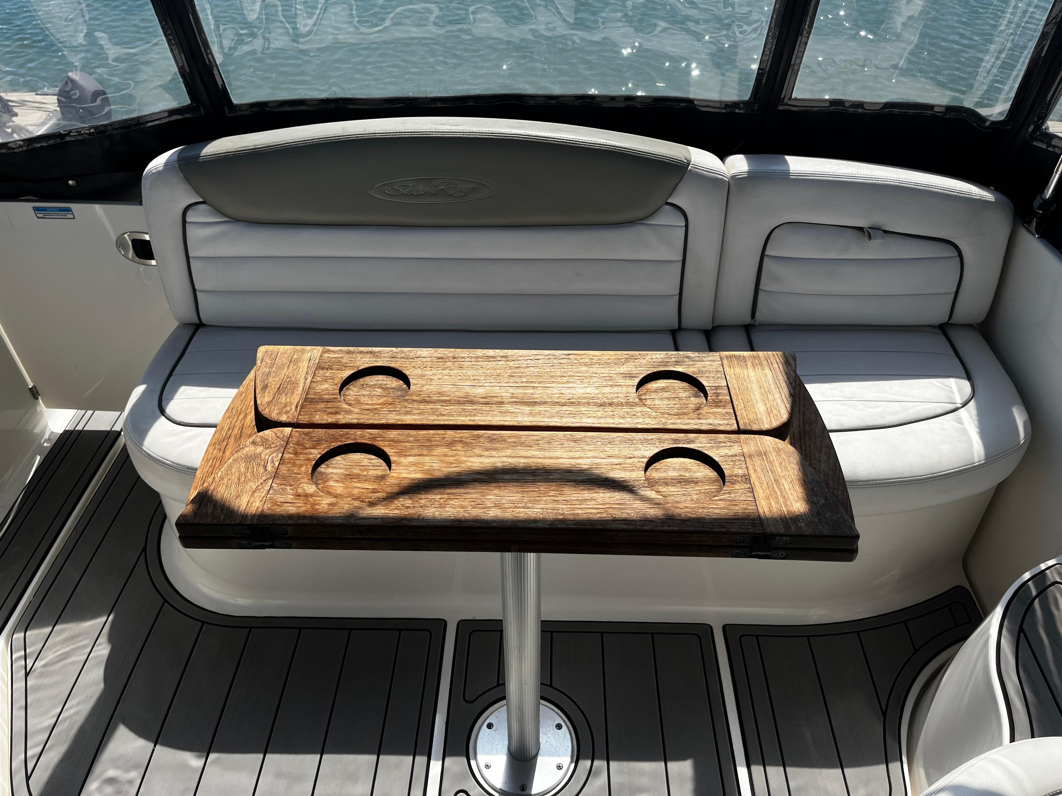 2006 Sea Ray 290 Sundancer interior with wooden table and cushioned seating.