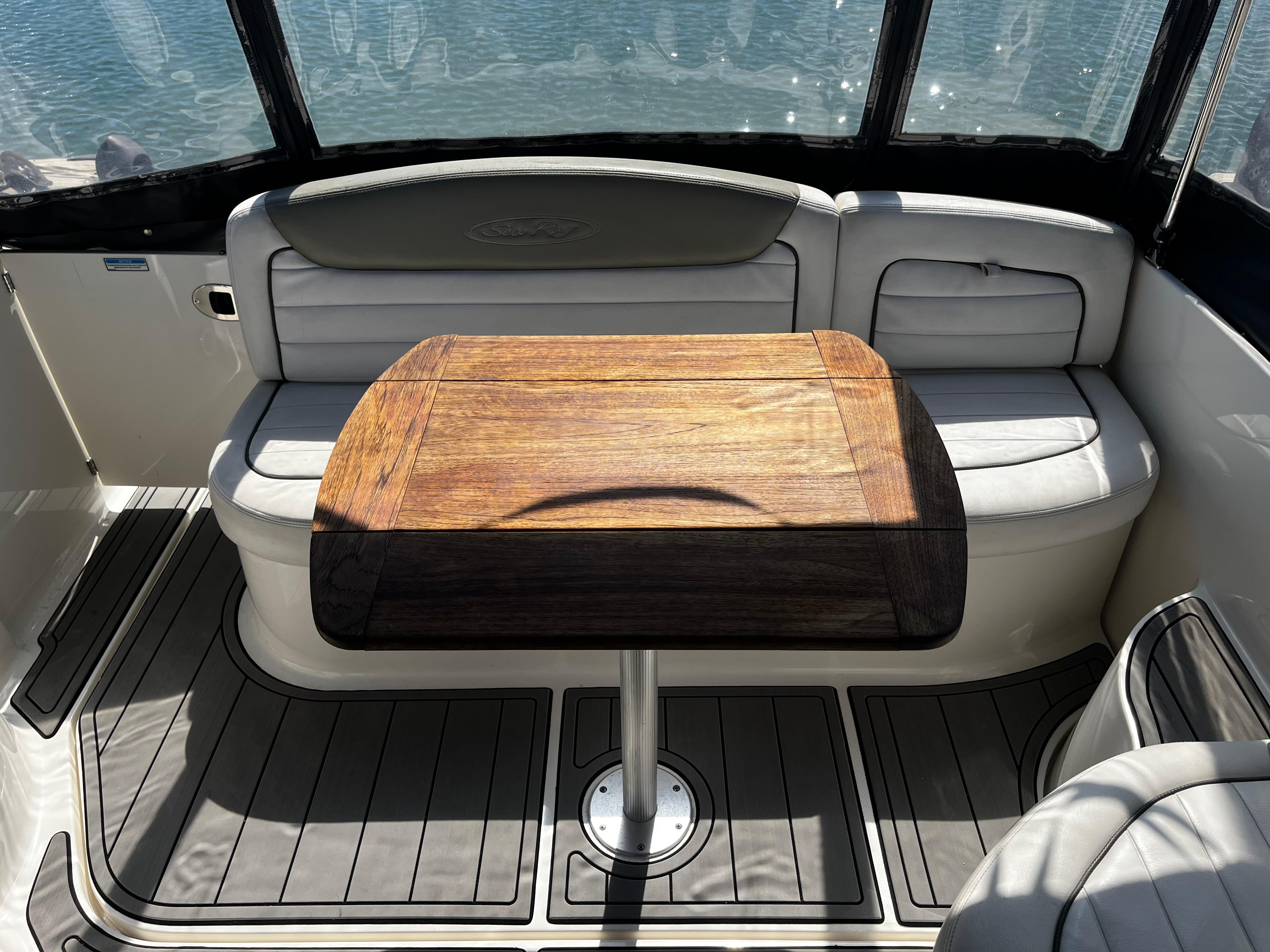 2006 Sea Ray 290 Sundancer interior with wooden table and cushioned seating.