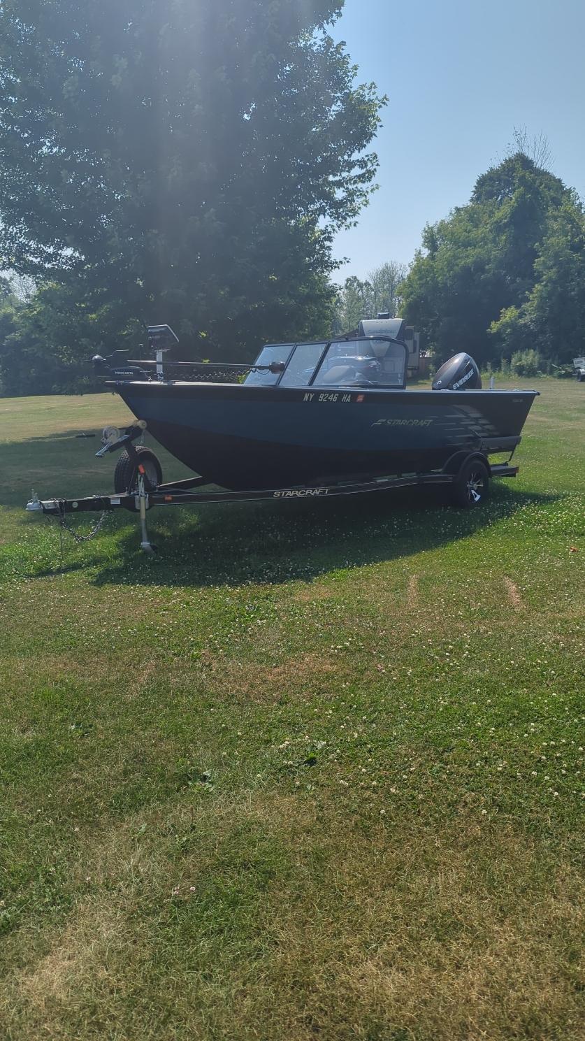 2019 Starcraft Titan 186 boat on trailer, parked on grassy area with trees in background.