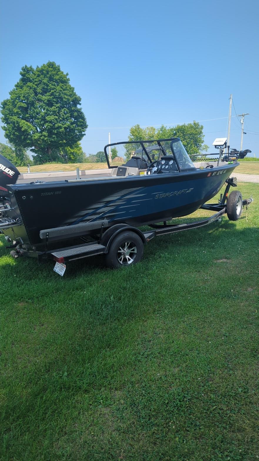 2019 Starcraft Titan 186 boat on trailer, parked on grass under clear blue sky.
